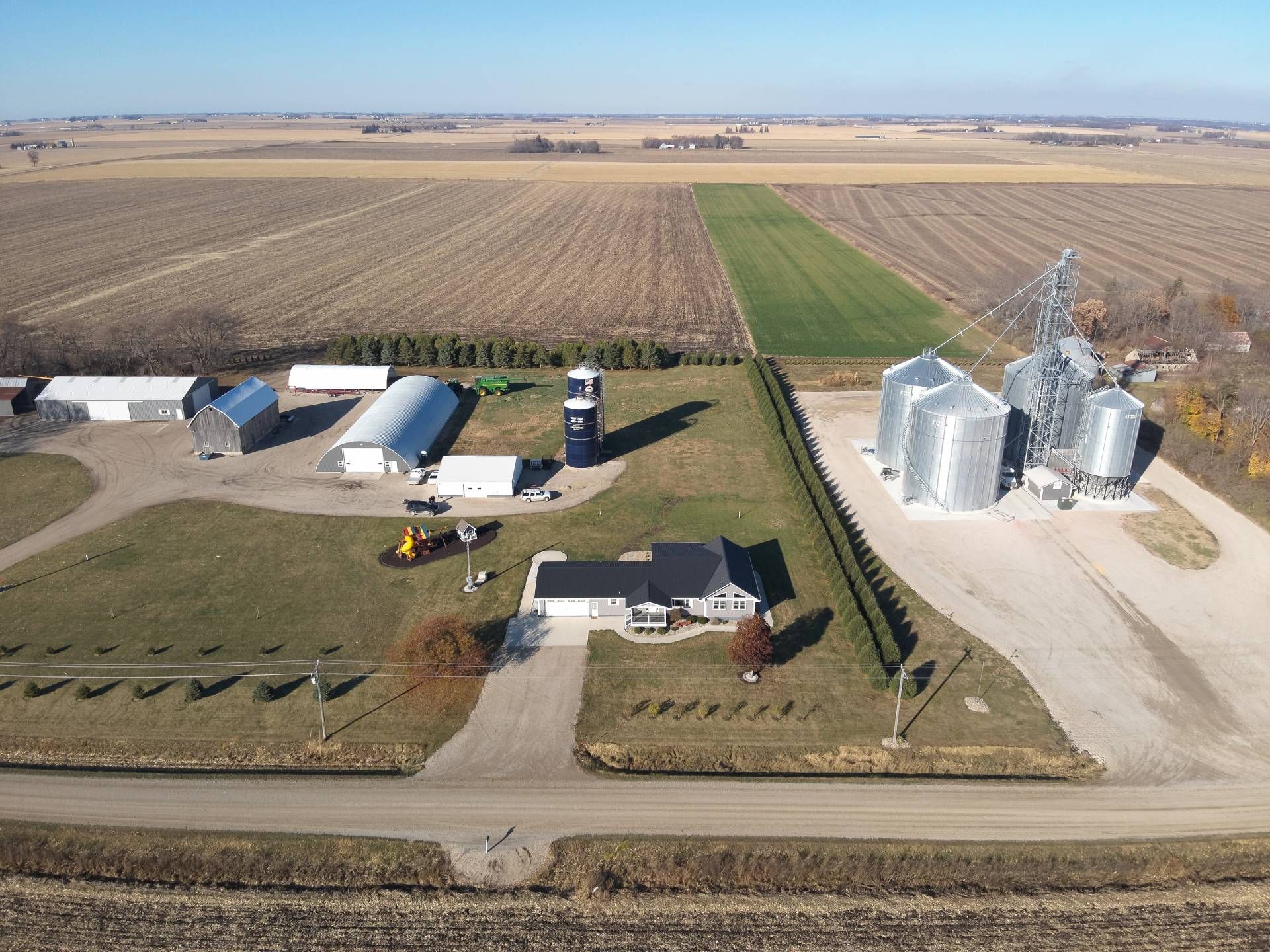 An aerial view of a farm with silos and a house