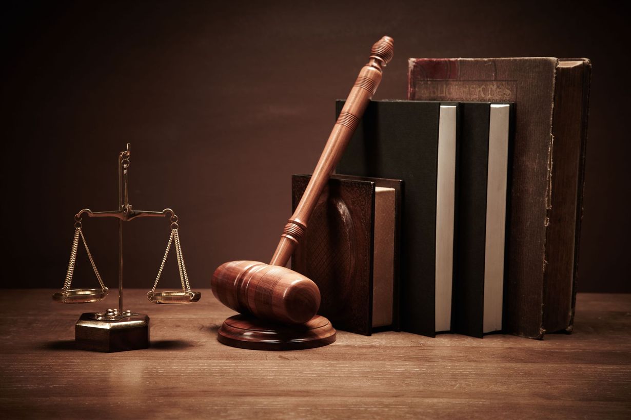 Wooden gavel, law books, and scales of justice on a dark desk