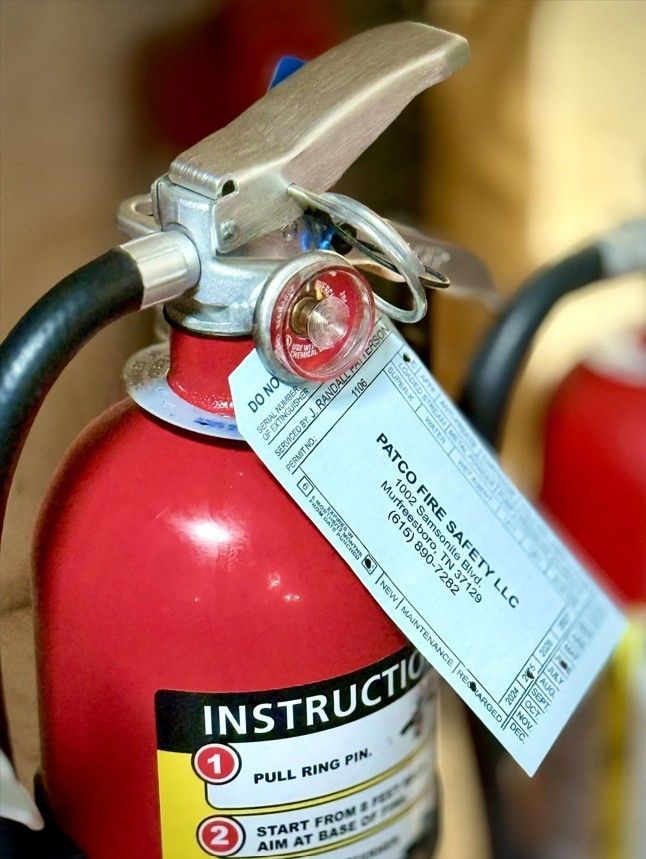 Red fire extinguisher with inspection tag, handle, and instructions.