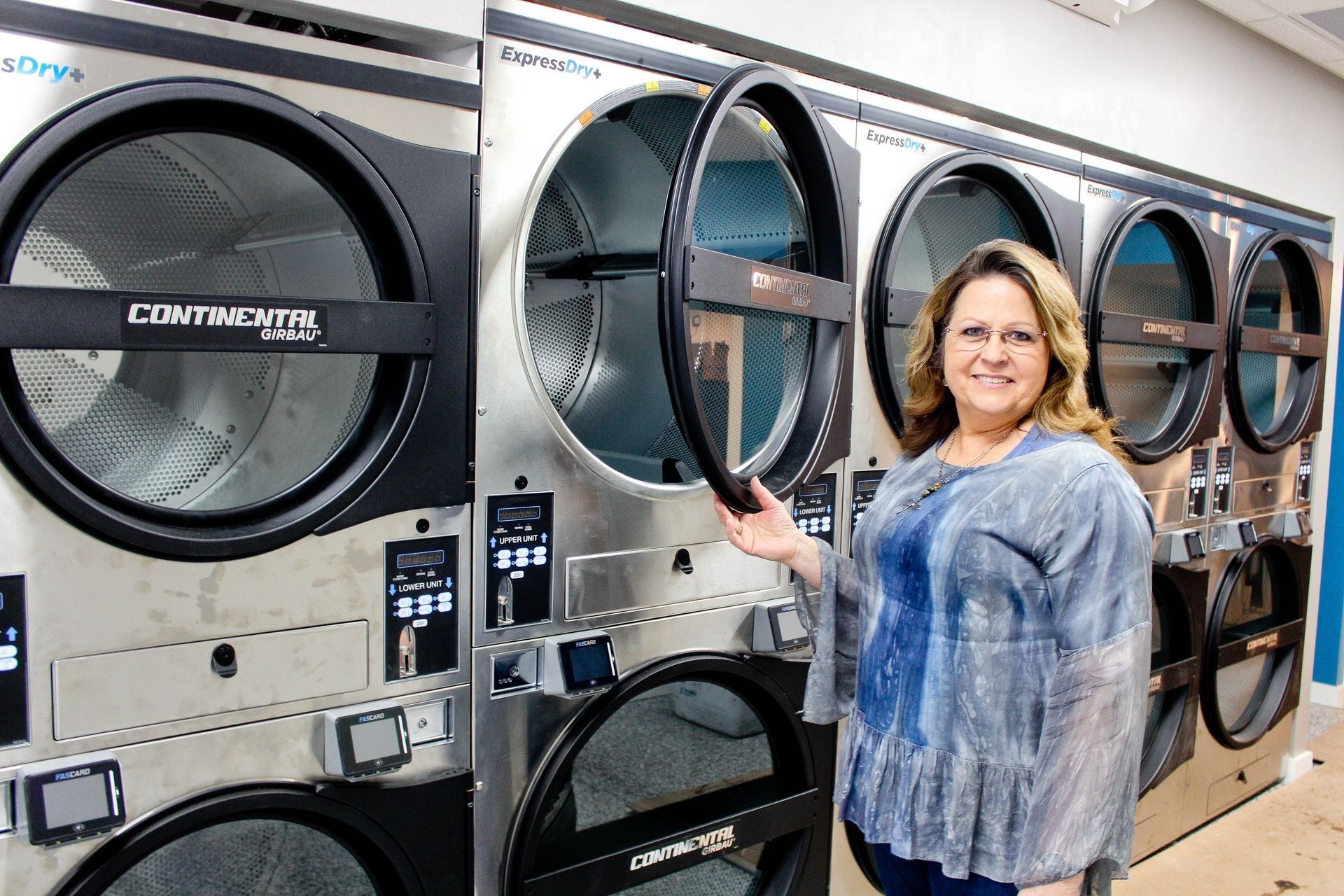 a woman is standing in front of a row of washing machines in a laundromat