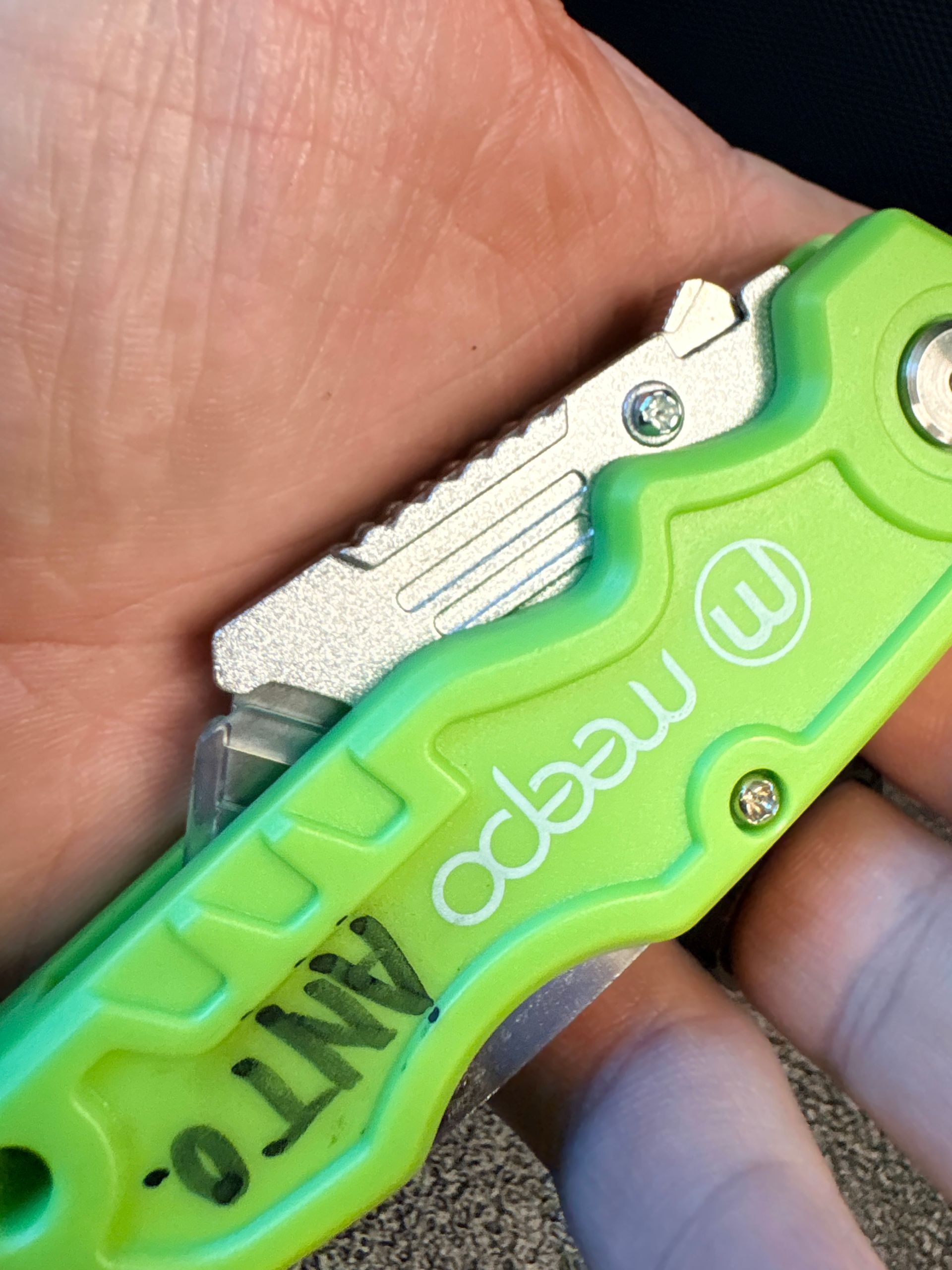 Close-up of a green and silver folding knife in a hand, with the word 