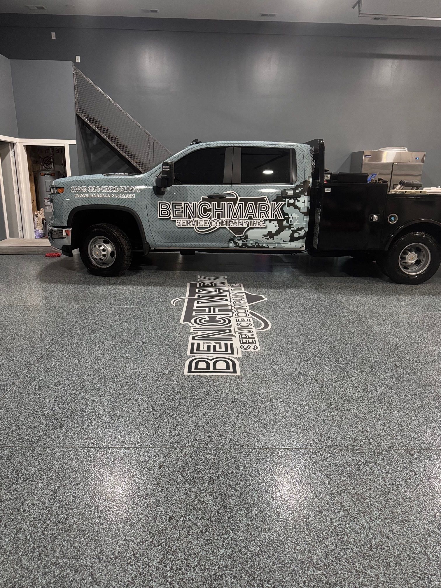 A truck with company graphics parked on a gray speckled floor inside a building.