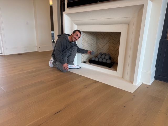 Man pointing at fireplace with decorative spheres in a modern room with wooden floors.