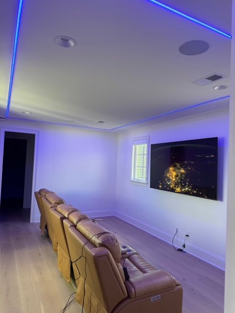Home theater with a large screen, reclining chairs, and blue LED lighting on the ceiling.