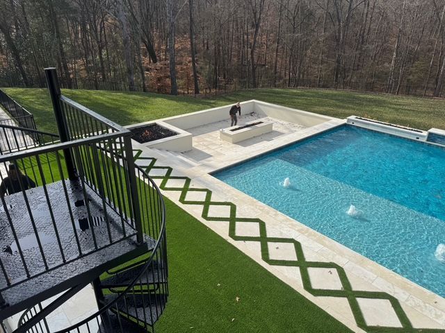 Pool area with a rectangular pool, manicured lawn, and black spiral staircase.