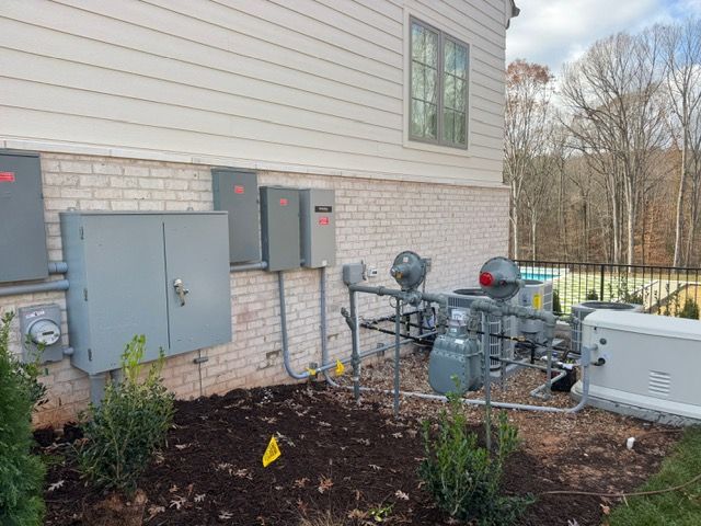 Exterior view of a house with electrical boxes and a gas meter system on a brick wall.