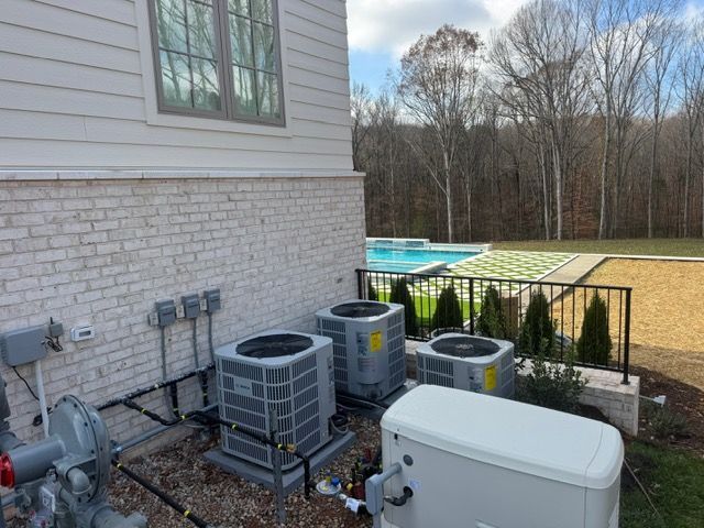 Air conditioning units and generator beside a house with a pool in the background.