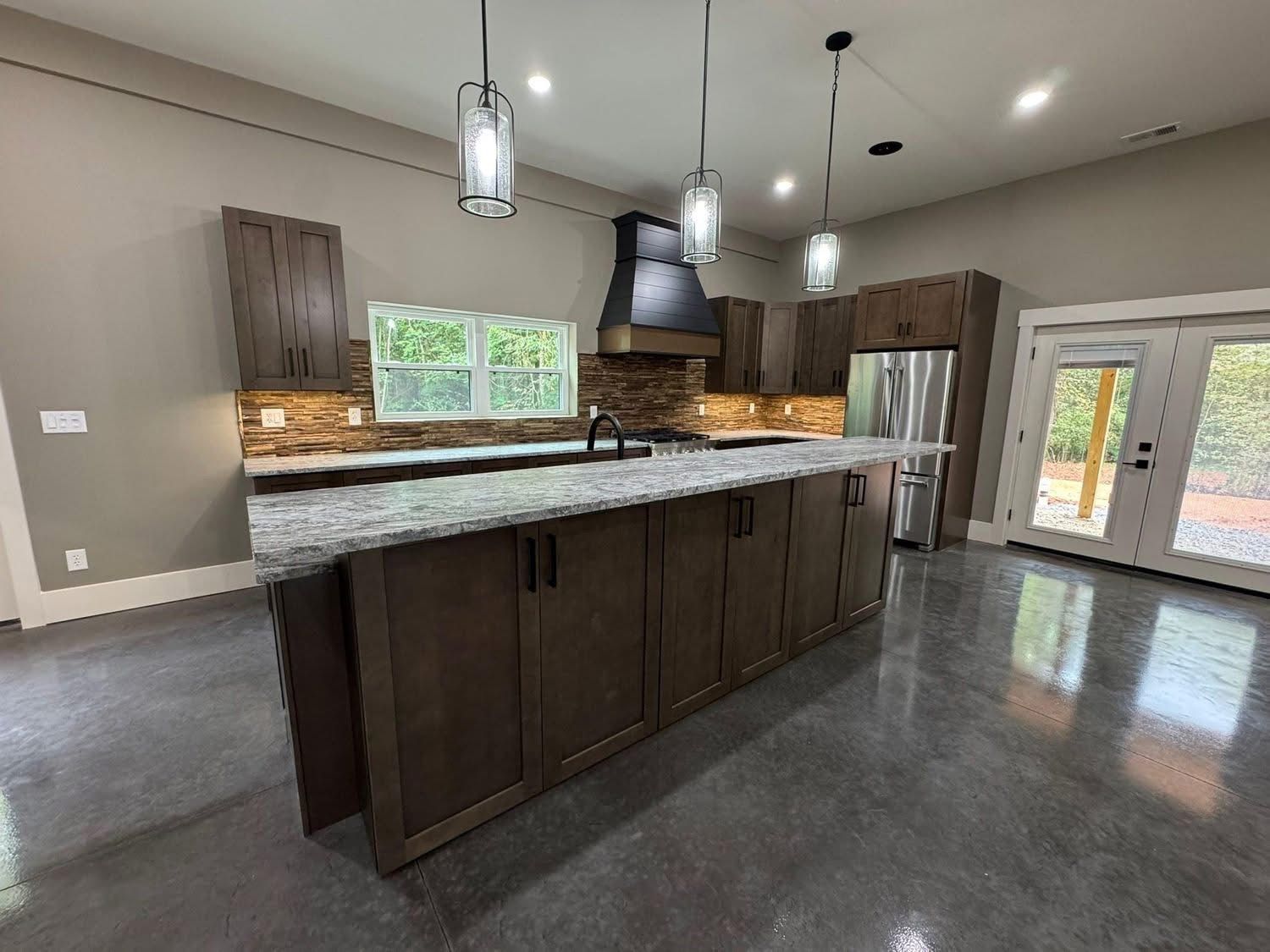 Modern kitchen with dark wood cabinets, gray countertop, and pendant lights.