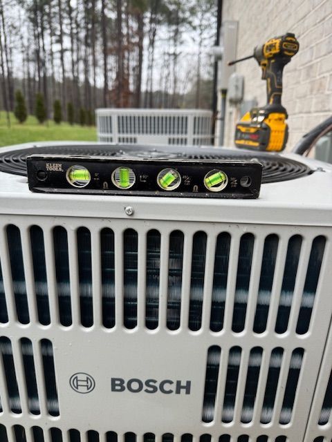 A level atop a Bosch AC unit, a drill is nearby.