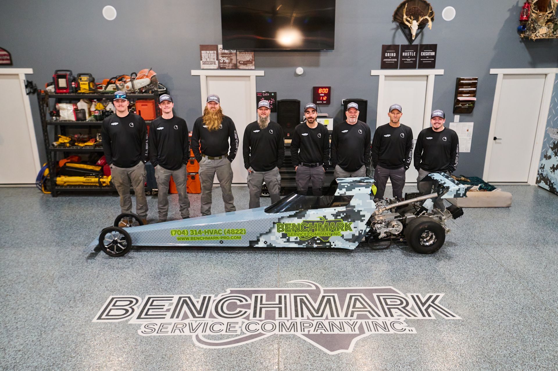 Group of people with a dragster in a garage.
