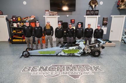 Group of people with a dragster in a garage.