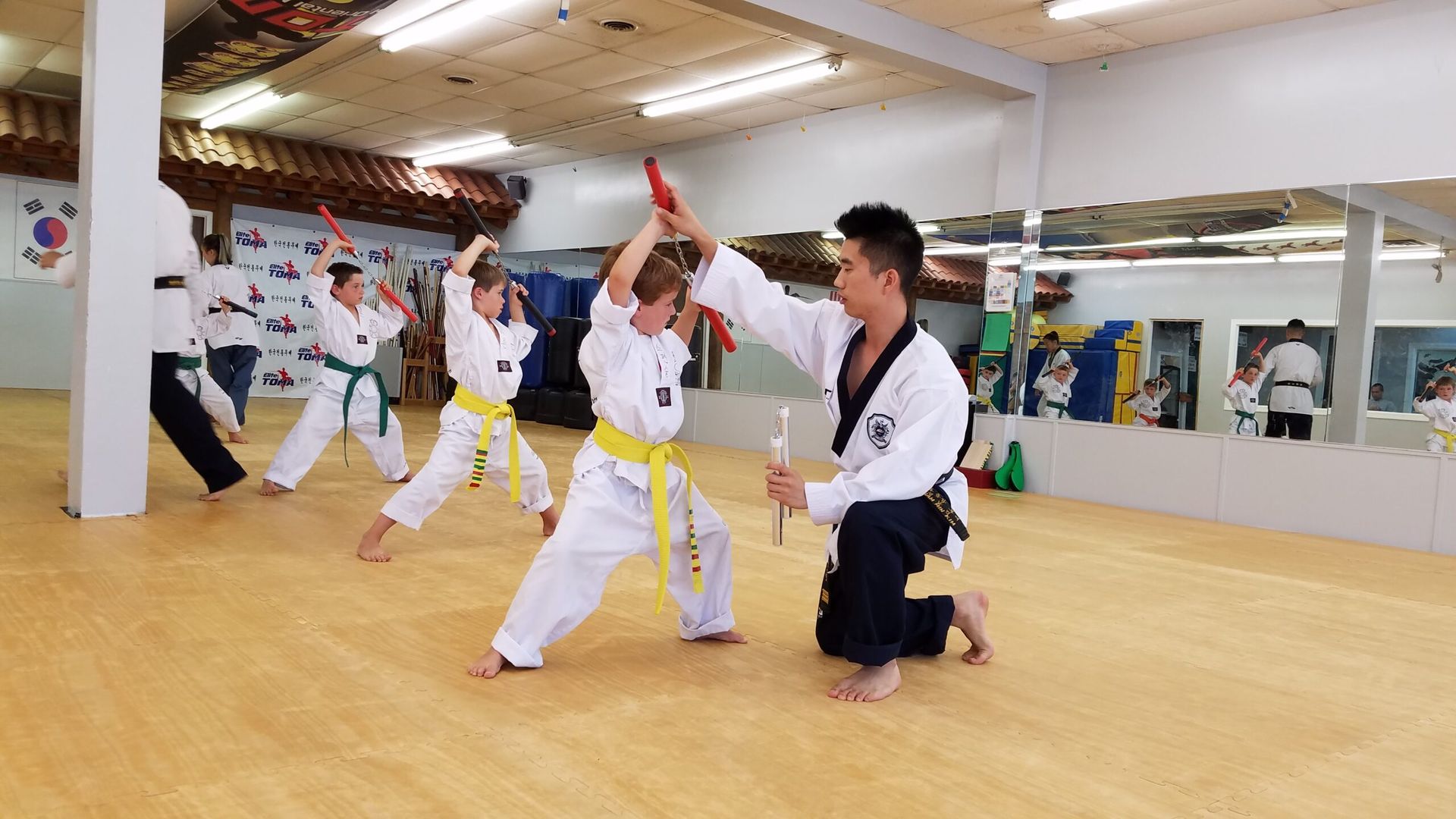 Martial arts instructor demonstrating baton techniques to students in a dojo.