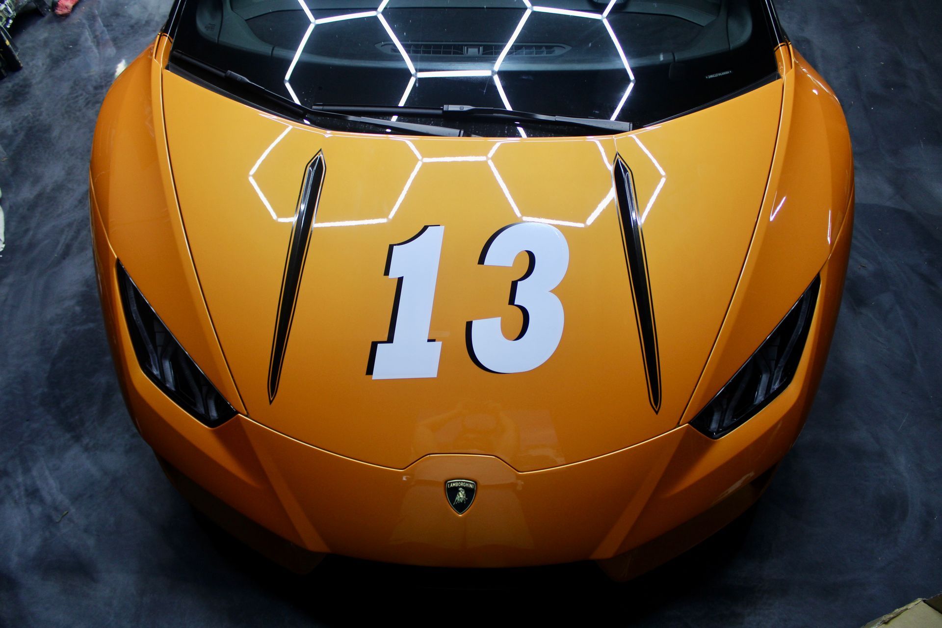 A bright orange Lamborghini hood with a large white number 