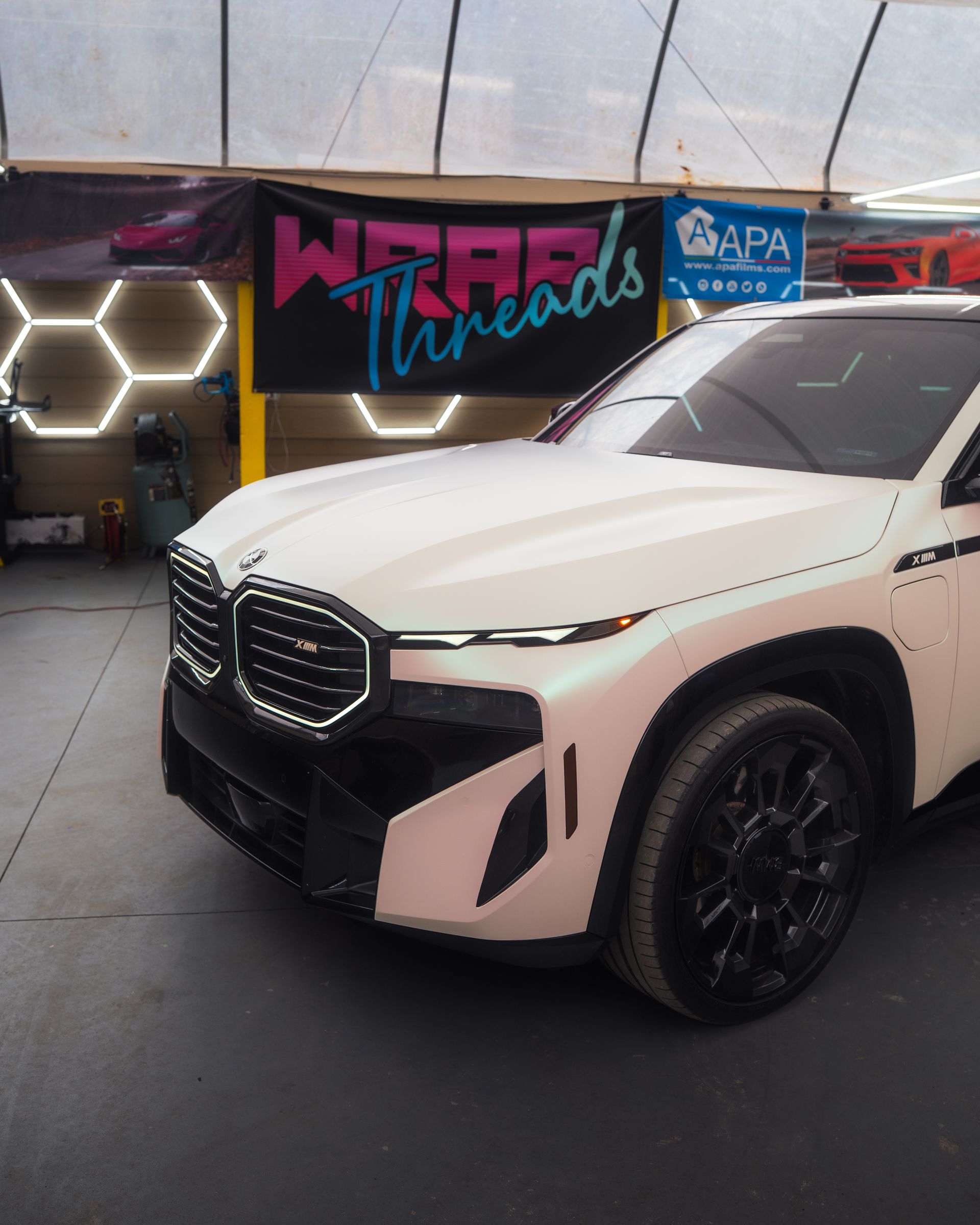 A white BMW XM parked in a garage with a 