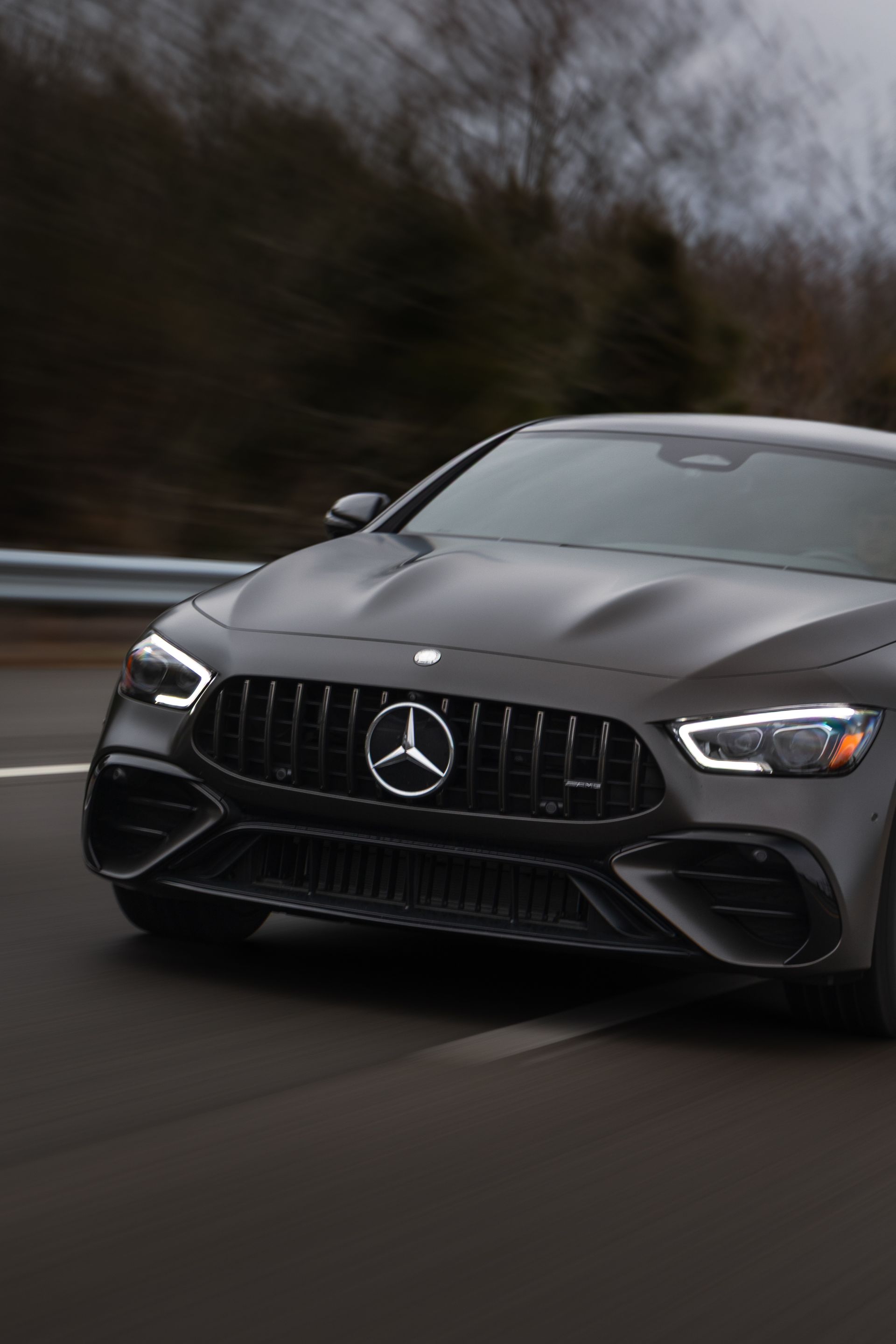 A matte grey Mercedes-AMG GT 4-Door Coupe driving on a blurred road.