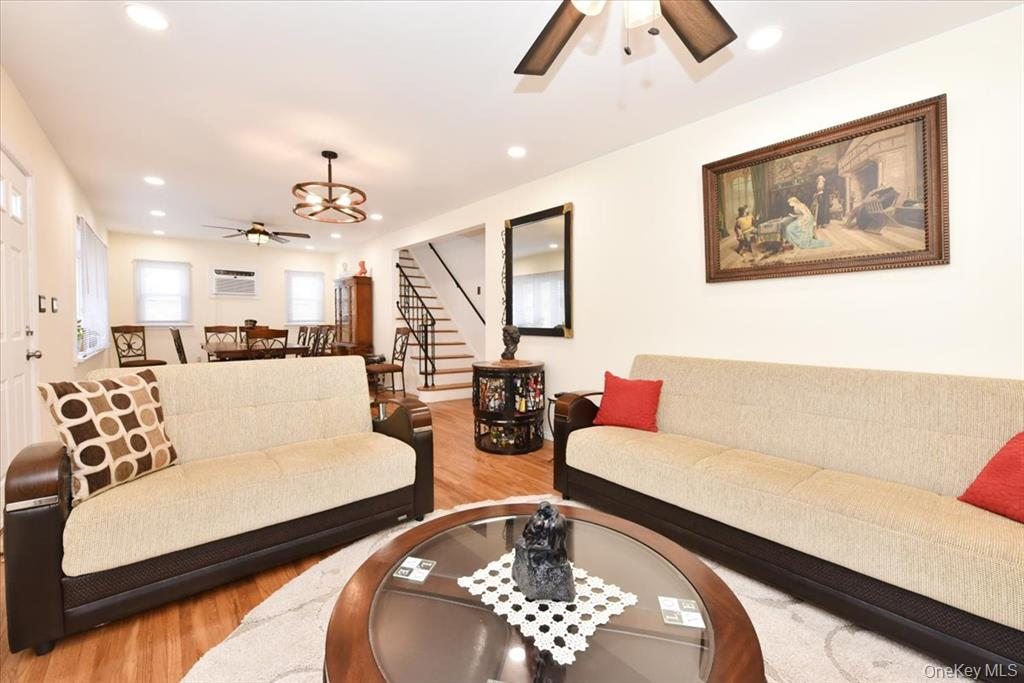 Living room with tan sofas, round coffee table, and dining area visible in the background.