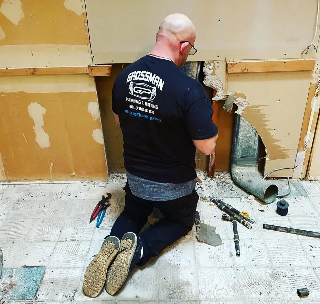 A man wearing a rossburn shirt is kneeling on the floor