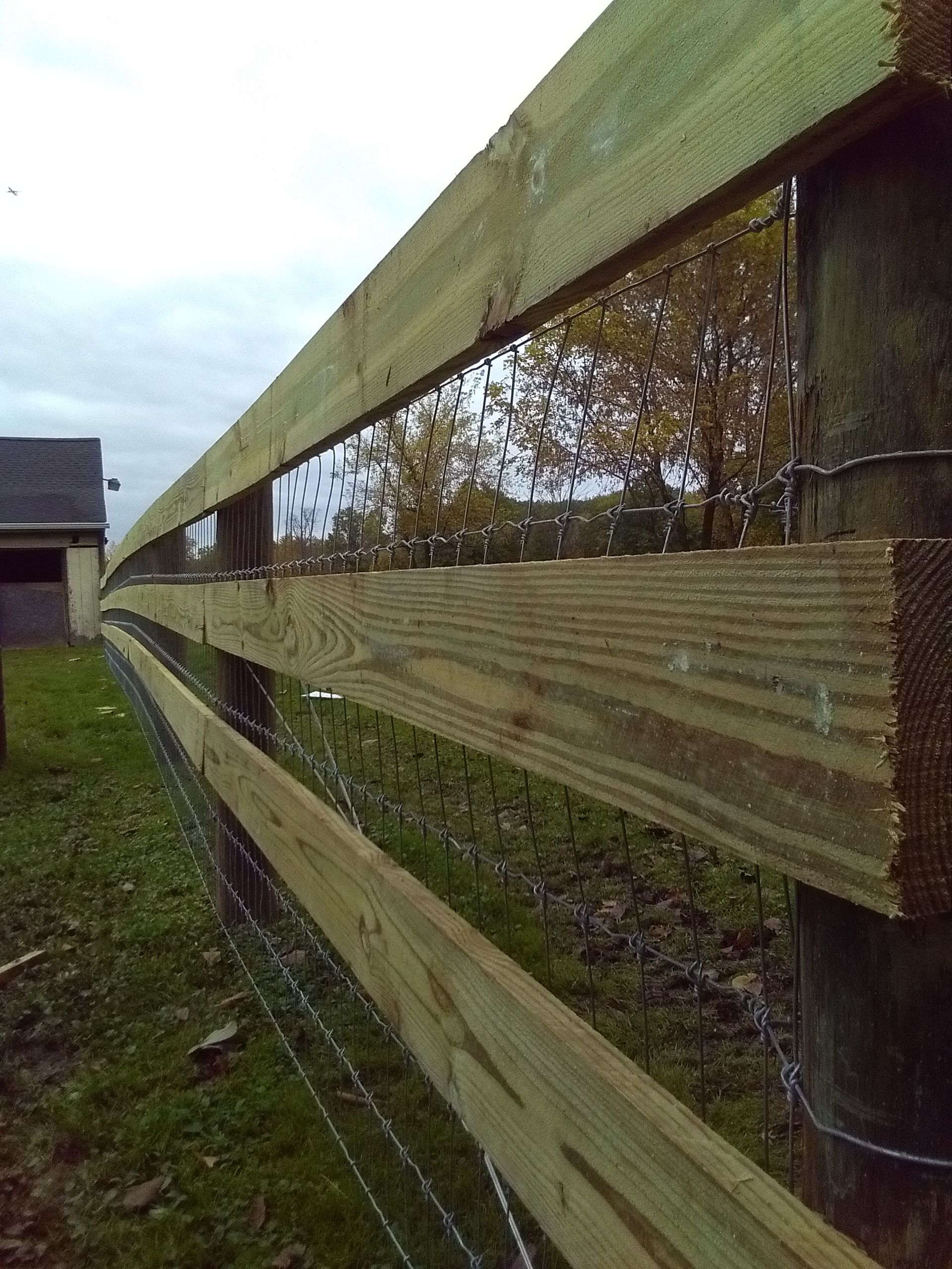 A wooden fence surrounded by grass and trees.