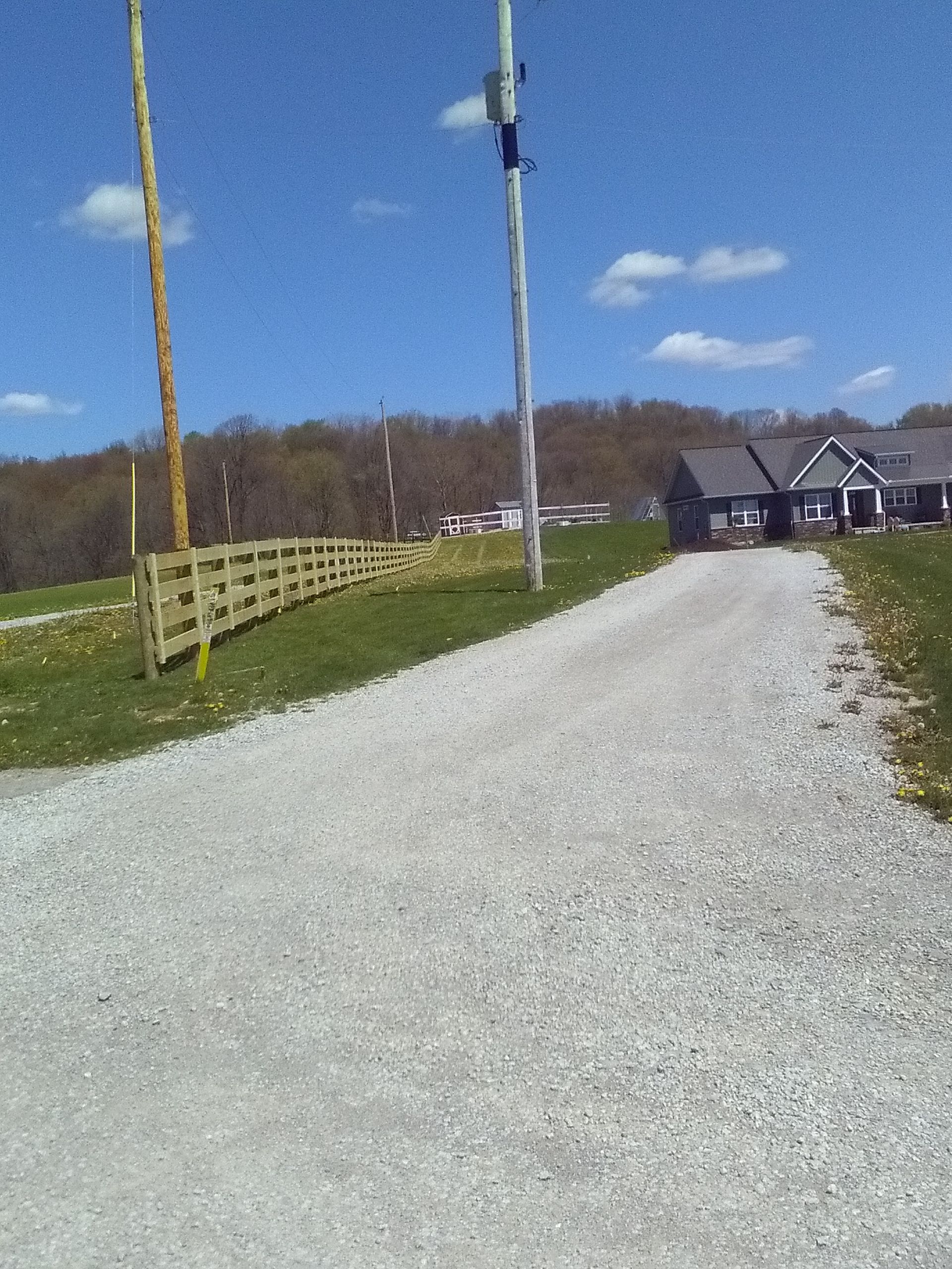 A gravel road leading to a house with a wooden fence