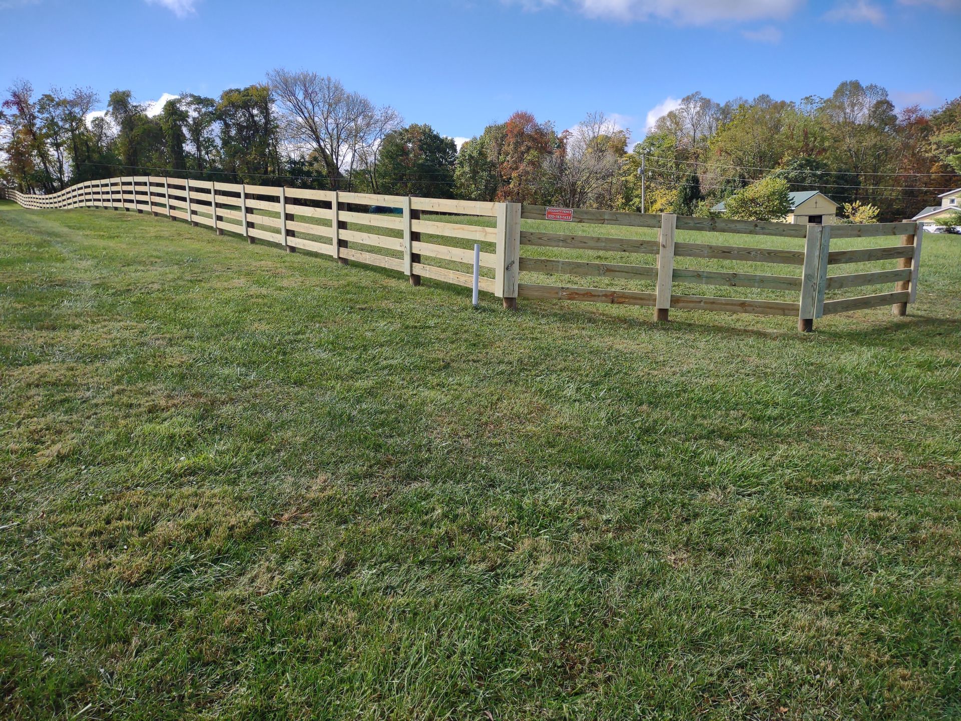 A wooden fence surrounds a lush green field.