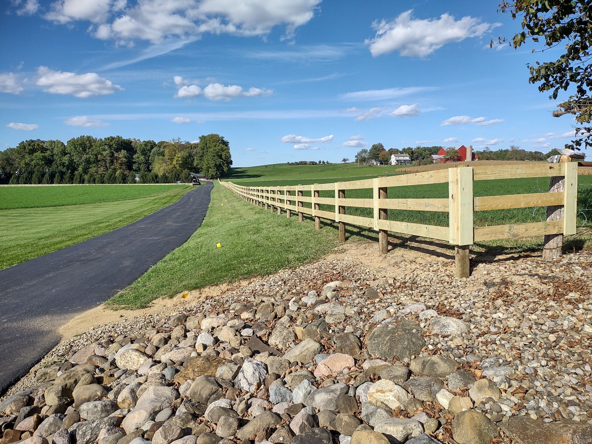 A wooden fence is along the side of a road.