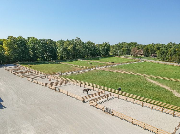 An aerial view of a horse farm with a horse in the middle of the field.