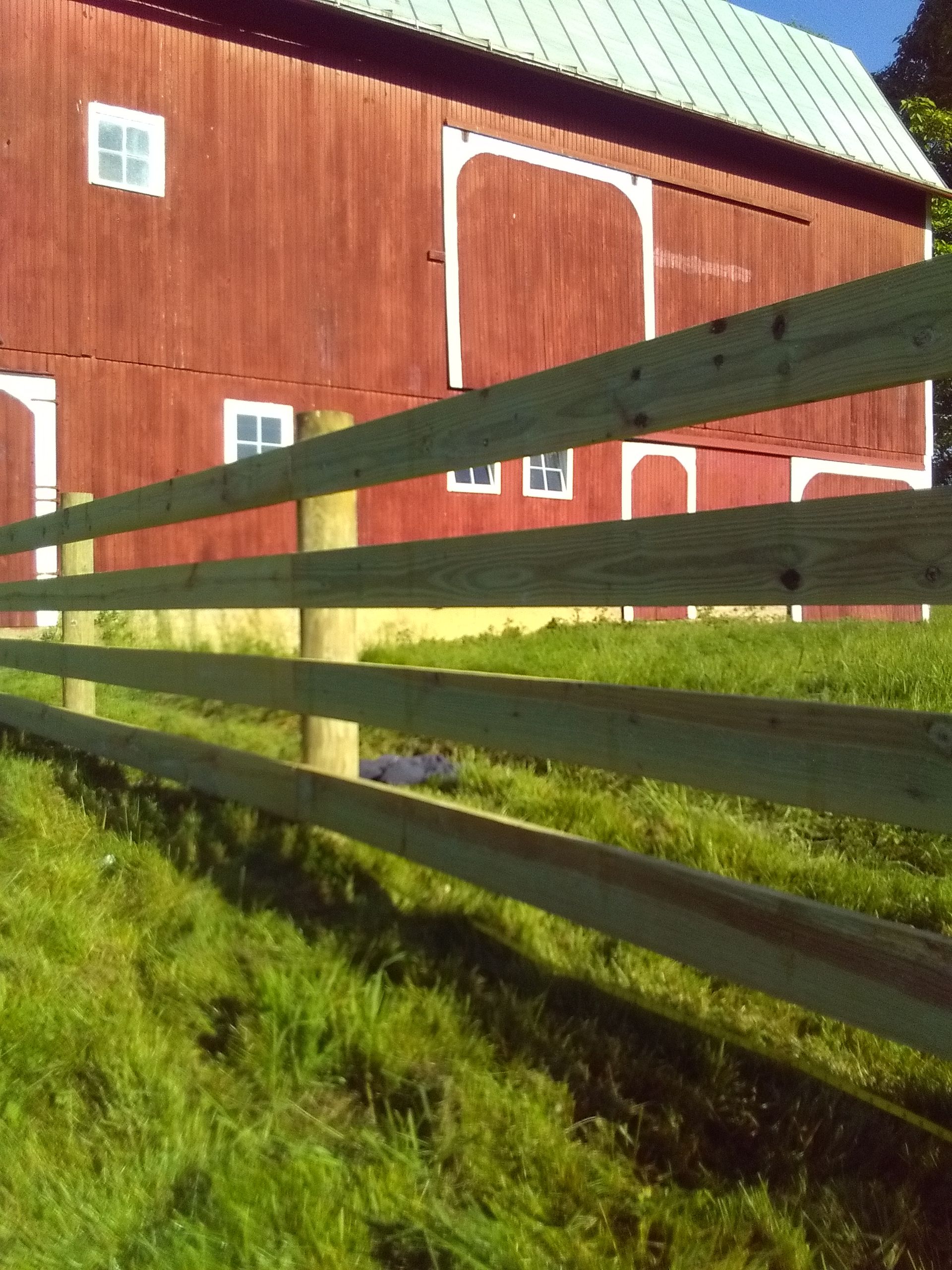 A wooden fence in front of a red barn