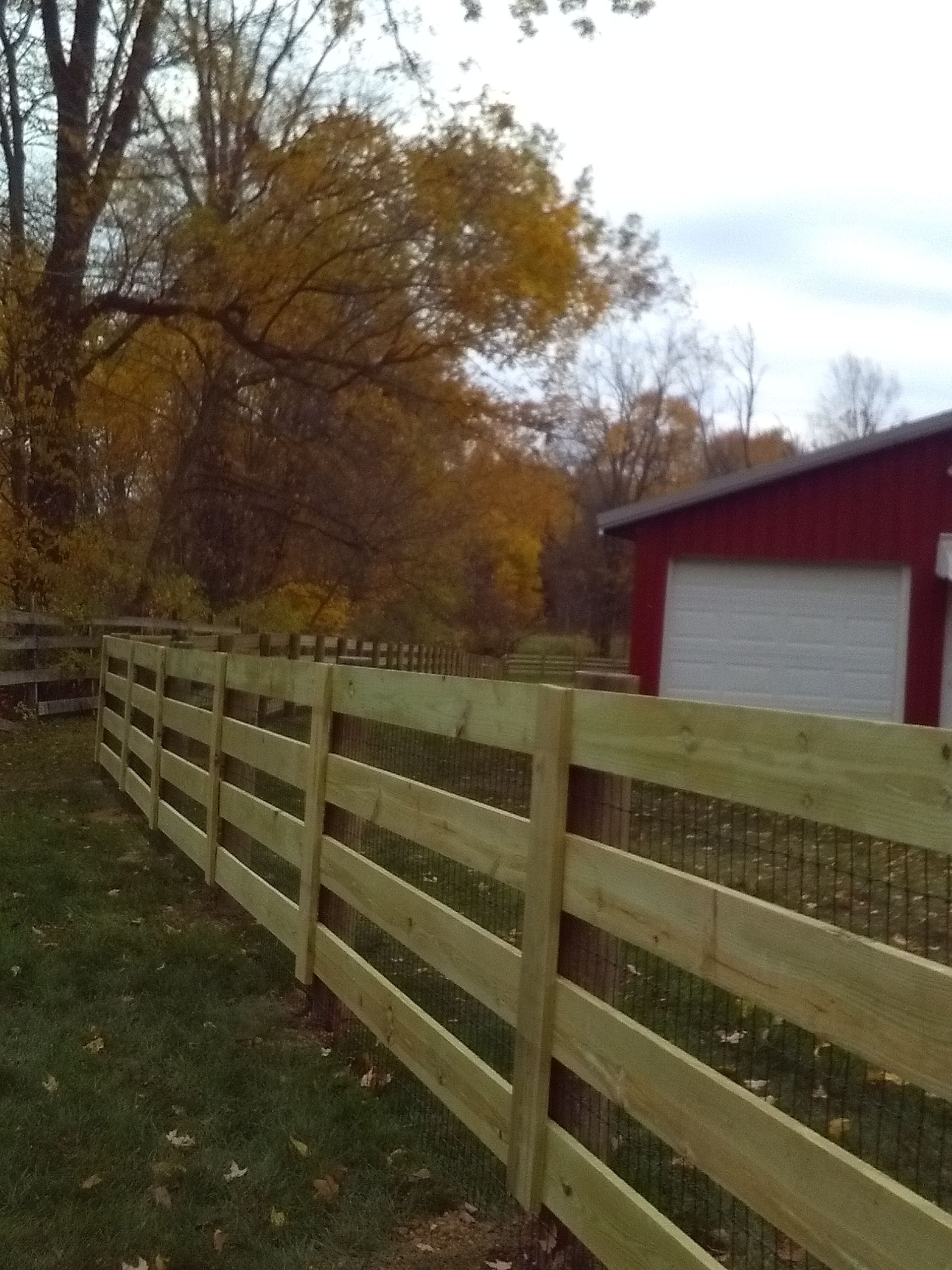 A wooden fence with a red garage in the background