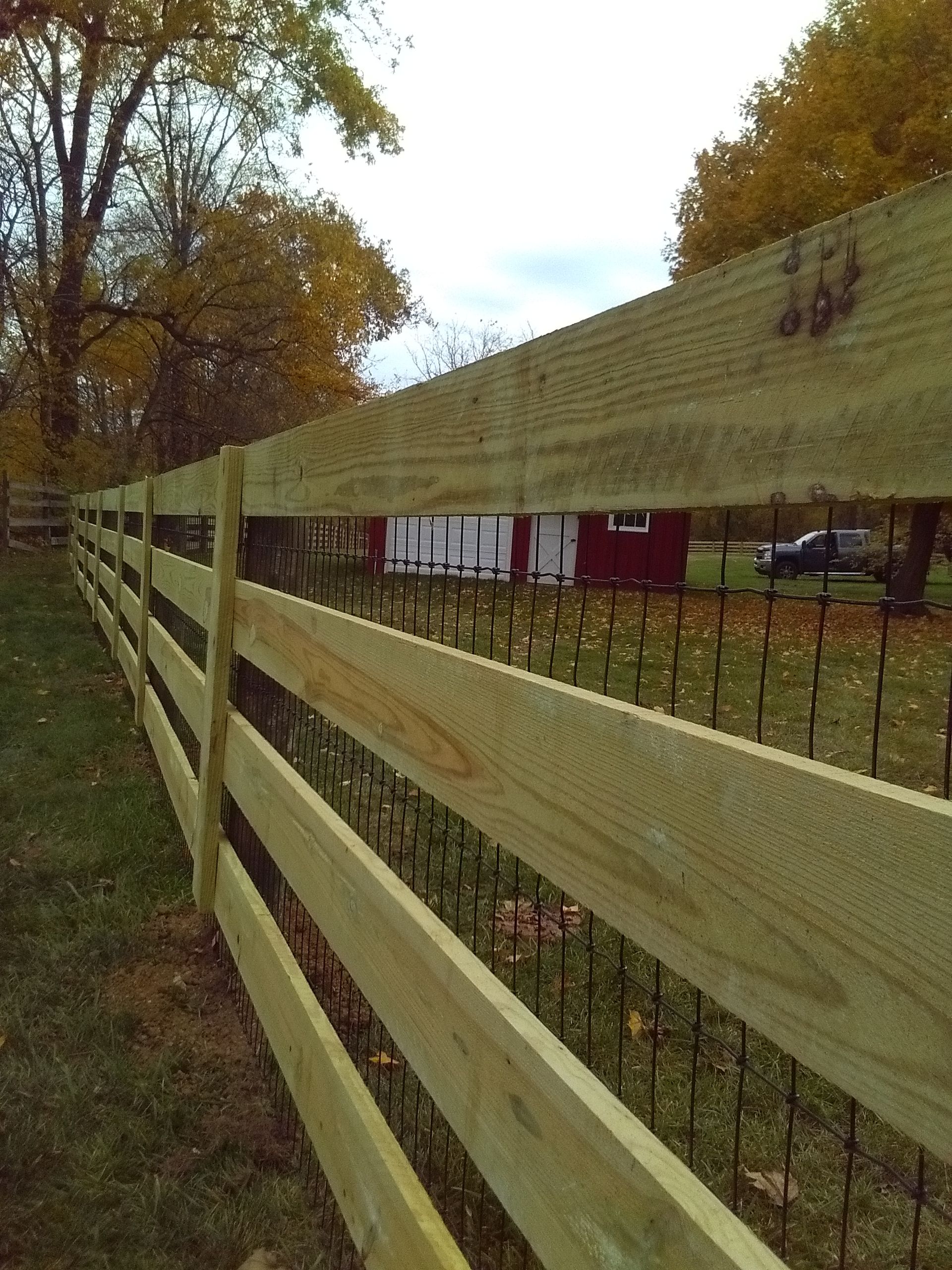 A wooden fence with a red barn in the background