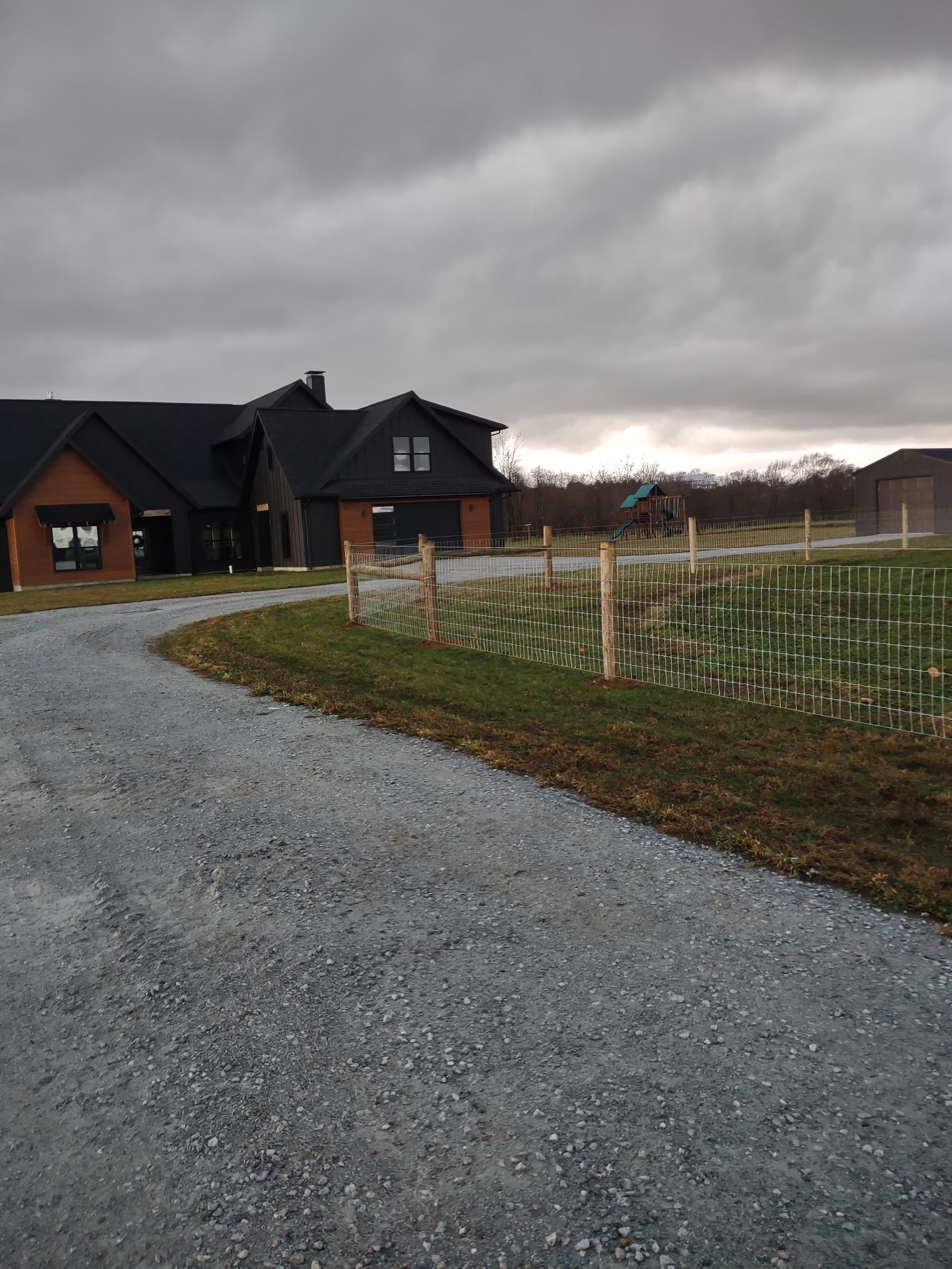 A gravel road leading to a house with a horse in the background