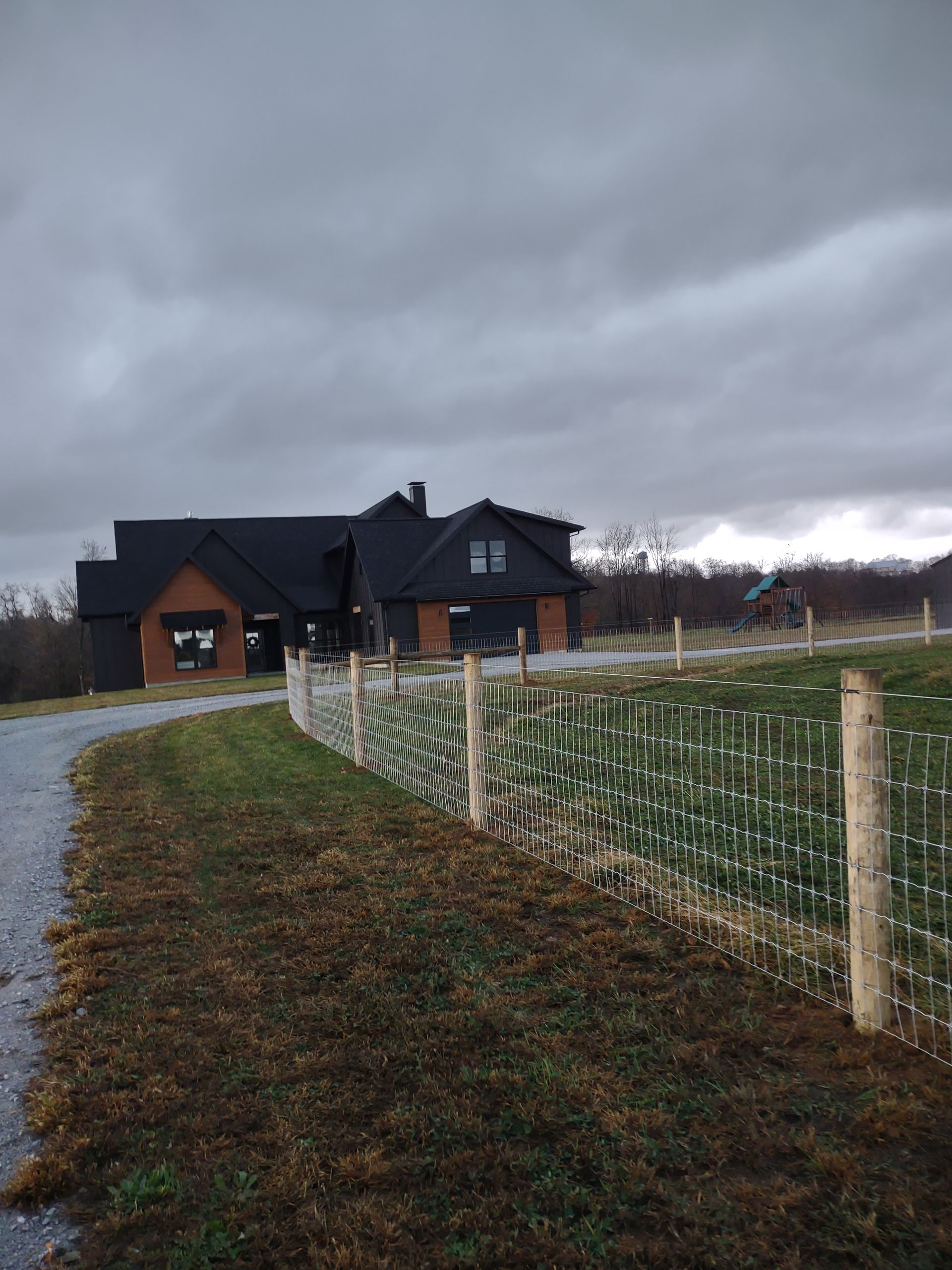 A house with a fence in front of it on a cloudy day