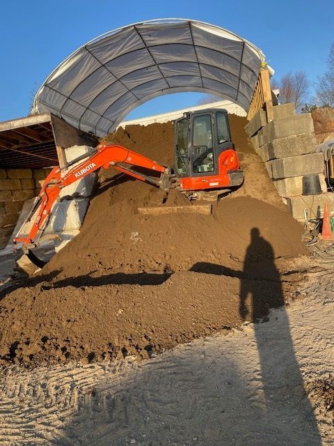 A large pile of dirt is being loaded by an excavator
