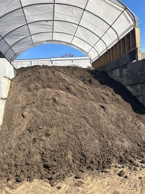 A large pile of dirt is under a white tarp.