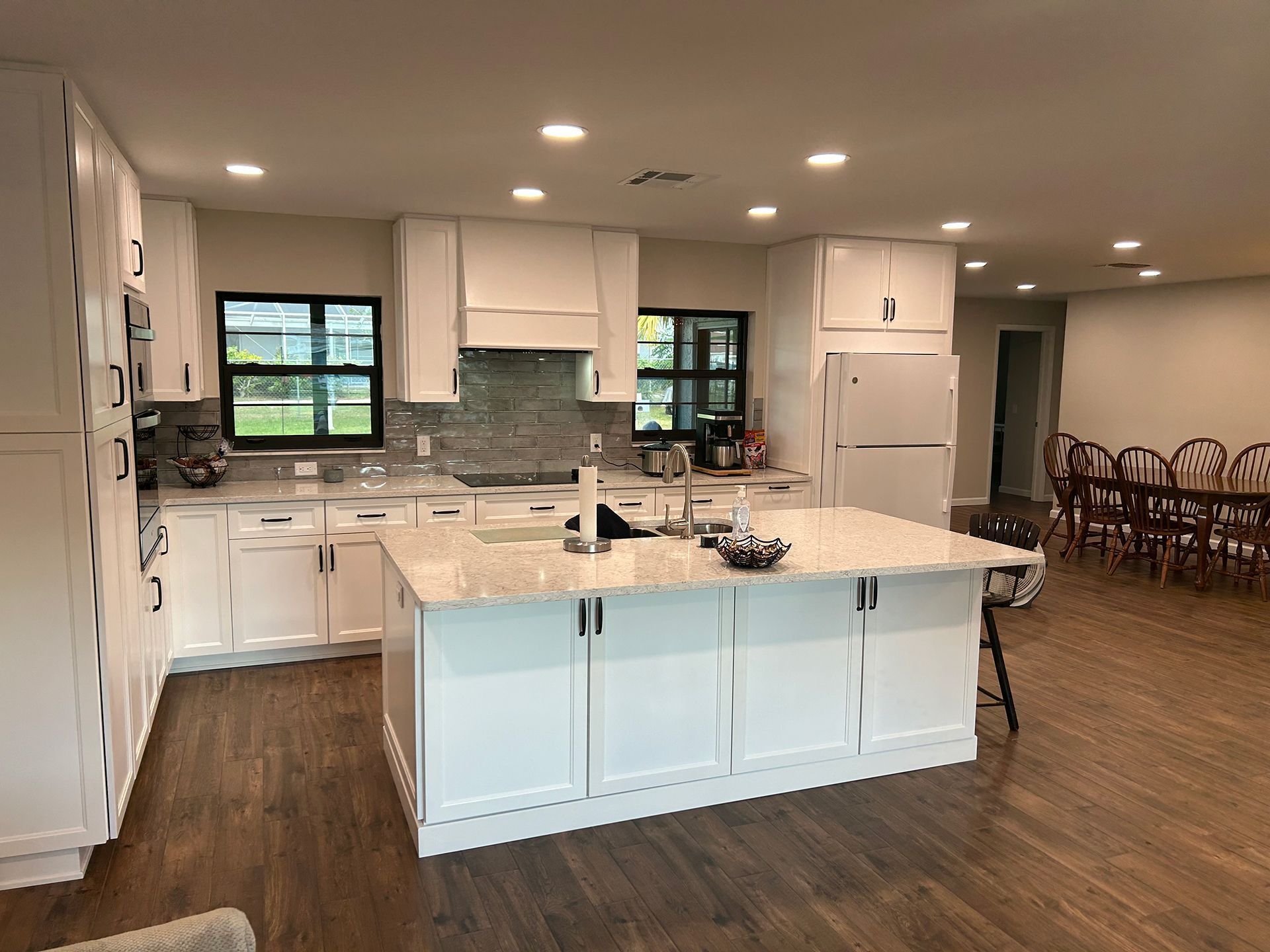 A kitchen with white cabinets and a large island in the middle.
