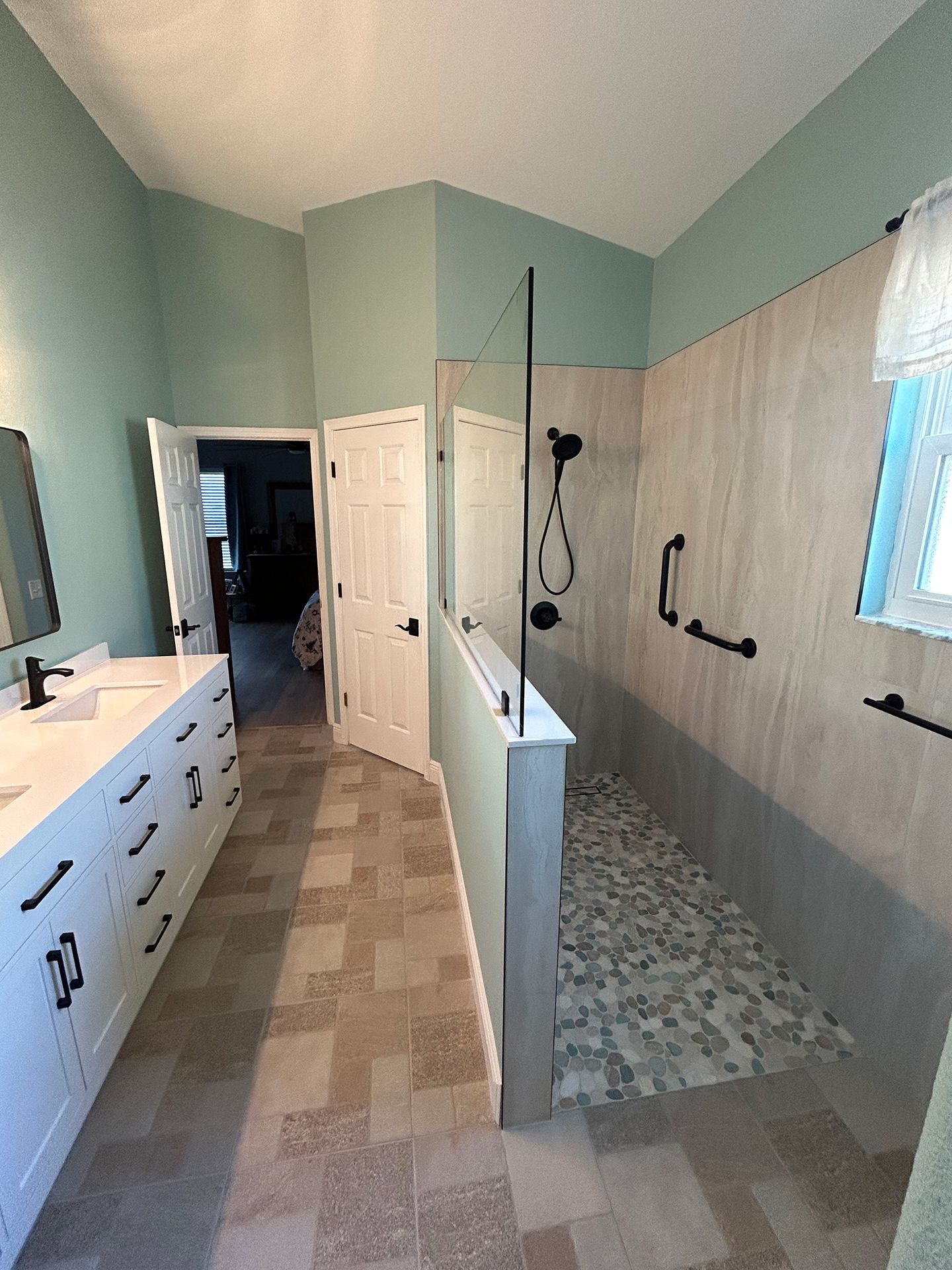 A bathroom with a walk-in shower, sink, and mirror