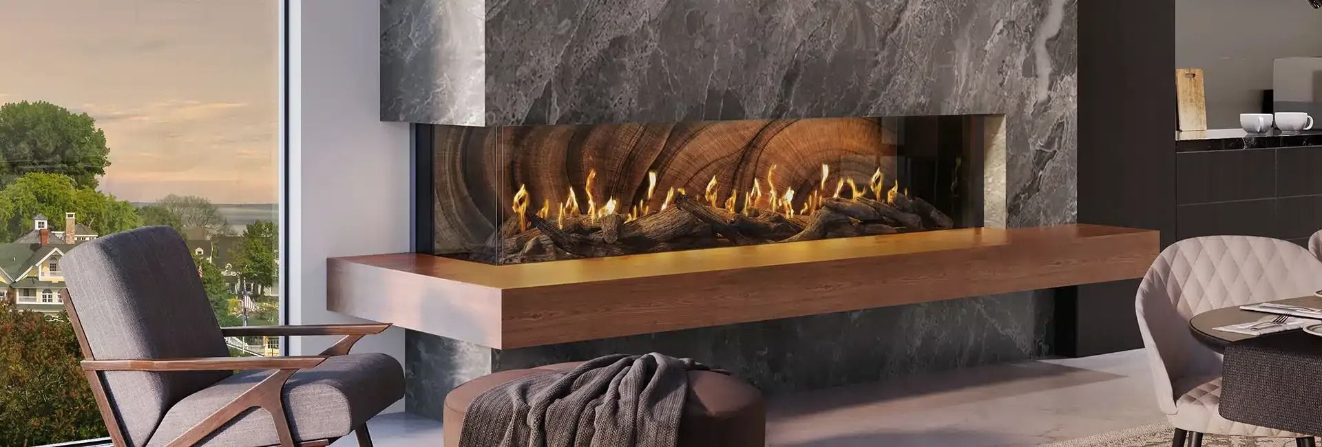 Fireplace with flames, wood mantle, stone surround, and seating area with a view of the outside.