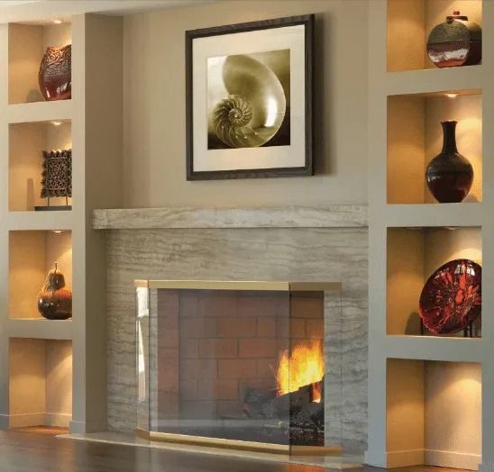 Fireplace with artwork and illuminated display shelves holding pottery.