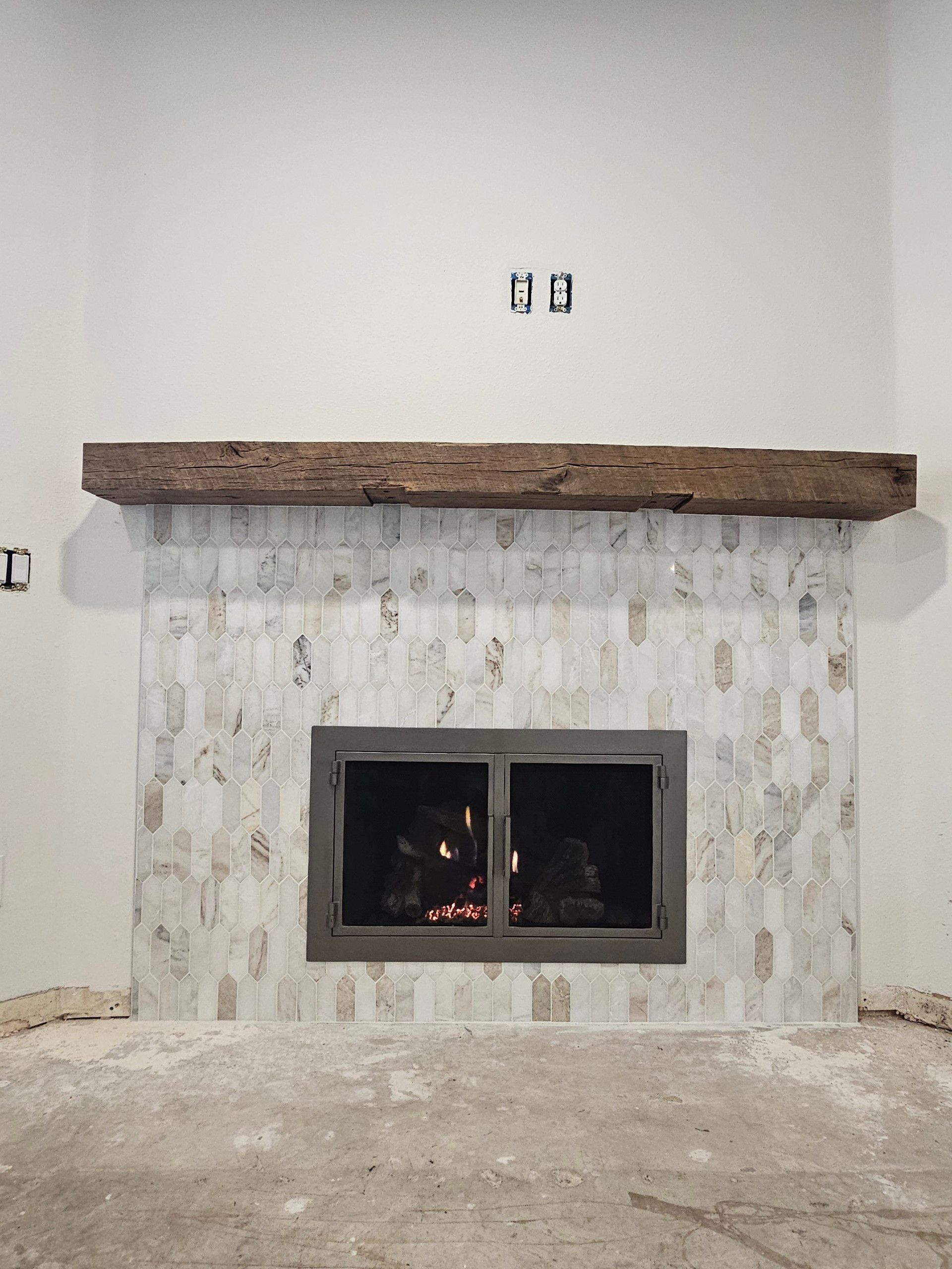Fireplace with stone tile surround, wooden mantel, and glass door.