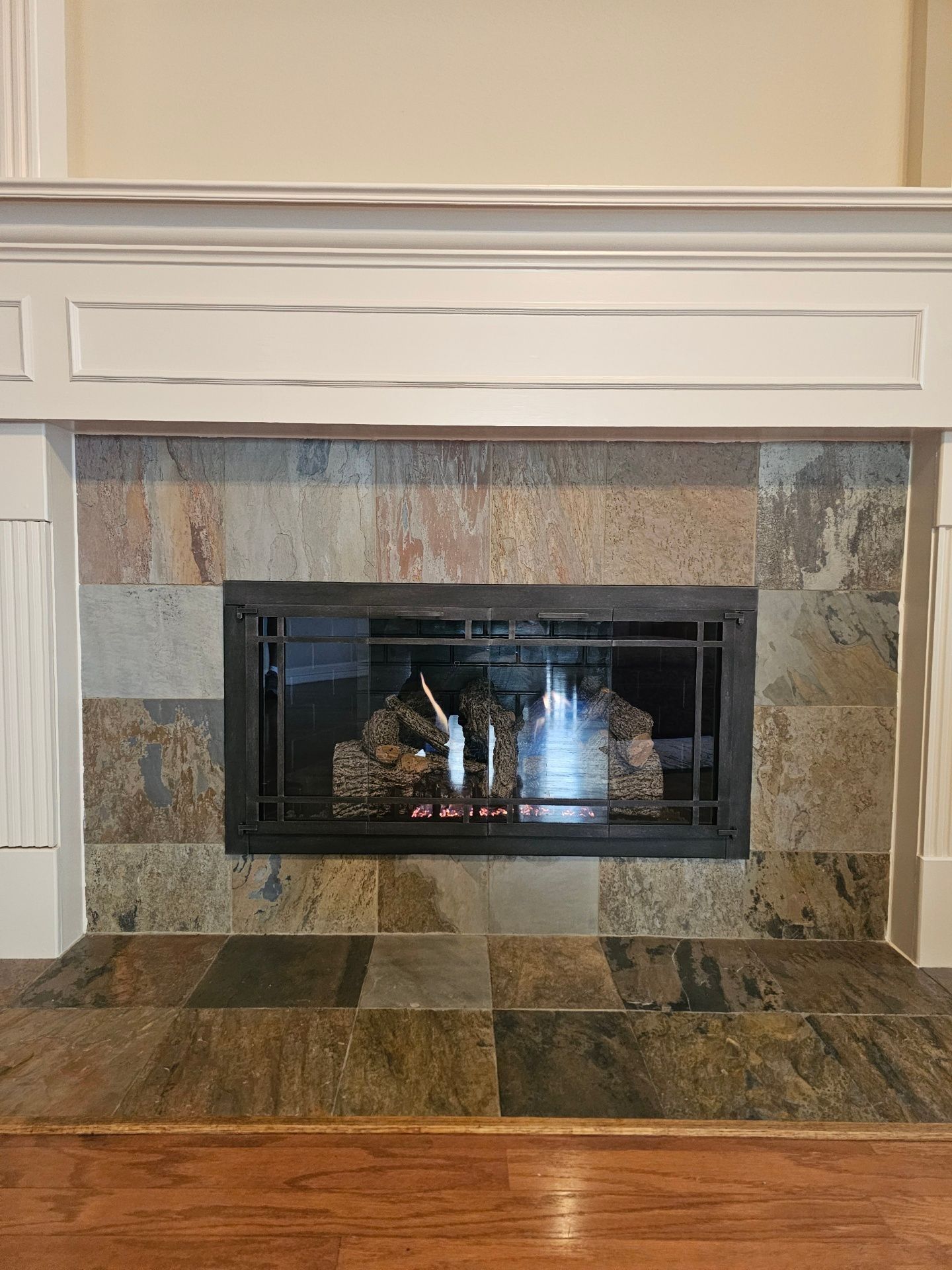 Fireplace with slate tile surround, white mantel, and burning logs.