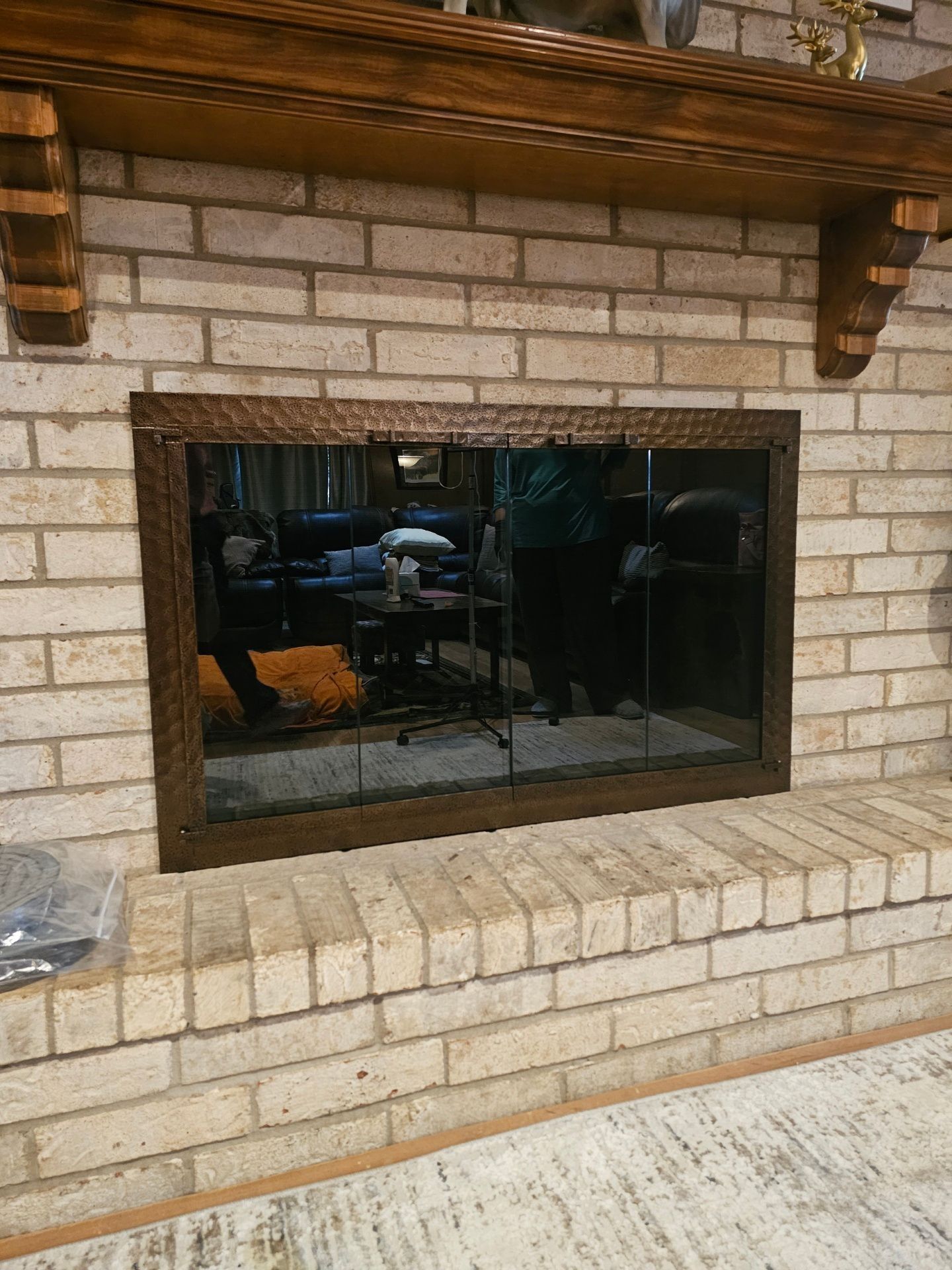 Fireplace with glass doors and brick surround, dark wooden mantel.