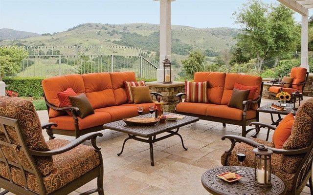 Outdoor patio furniture set with orange cushions and a scenic vineyard view.