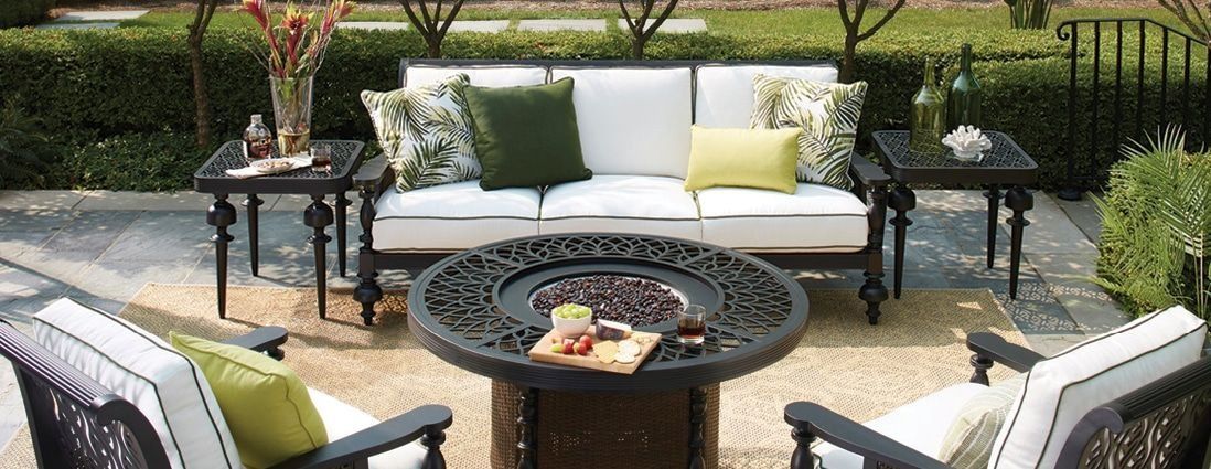 Outdoor patio set with a fire pit, a sofa with cushions, and two armchairs.
