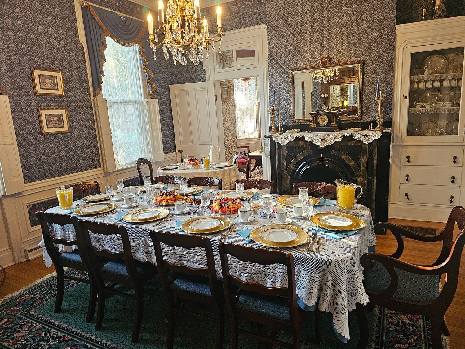 Formal dining room with a long table set for a meal. A chandelier hangs above.