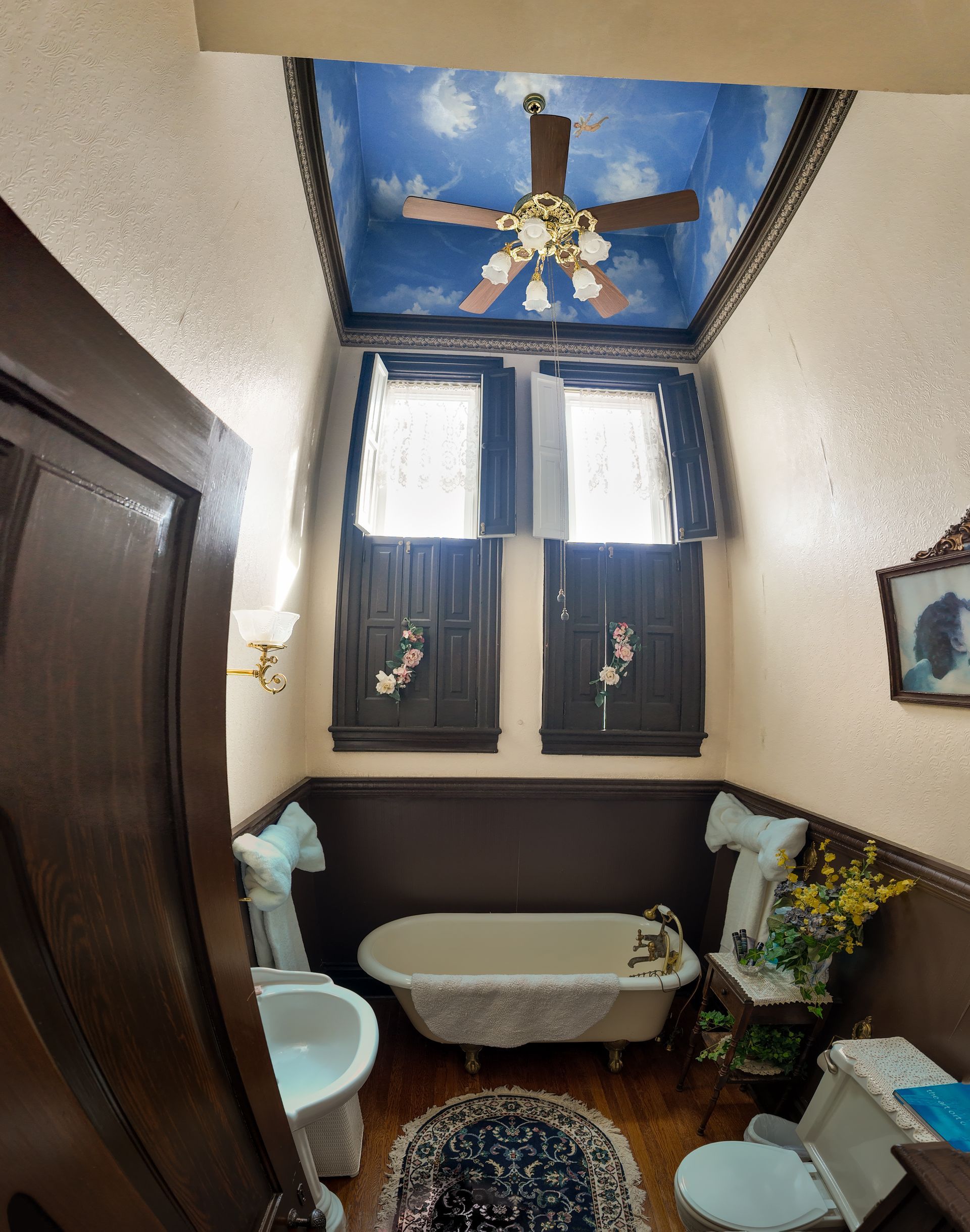 Bathroom with a painted sky ceiling, dark wood trim, clawfoot tub, and vintage fixtures.