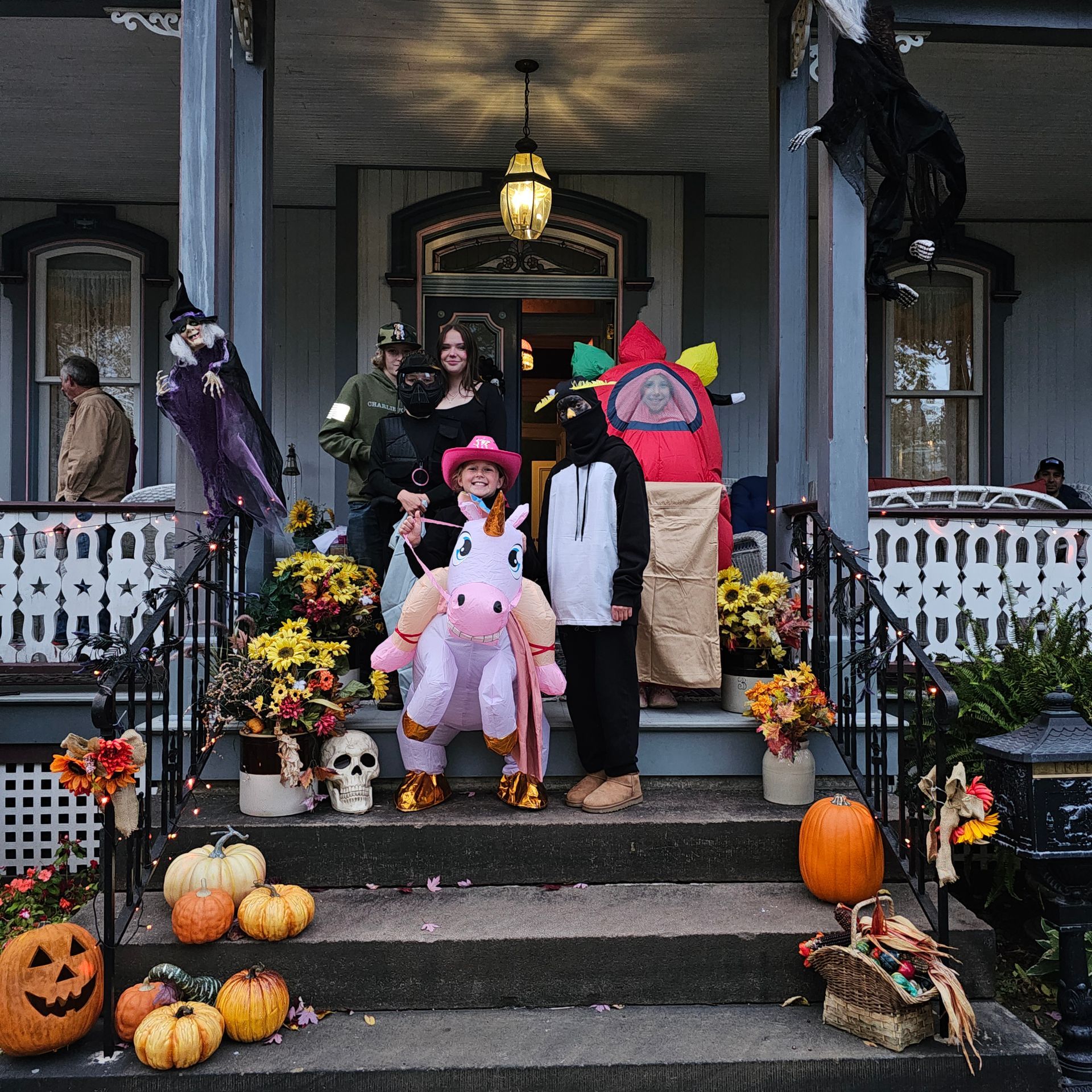 A group of people in halloween costumes are standing on a porch