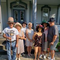 A group of people are posing for a picture in front of a house.