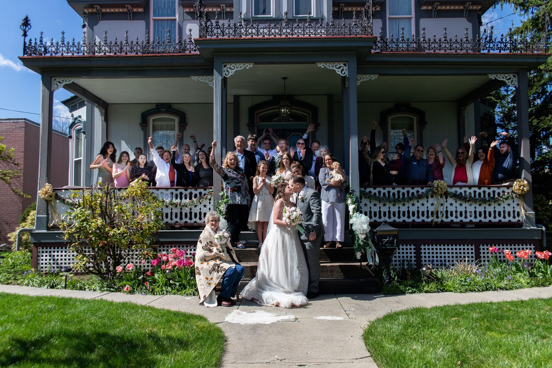 A large group of people are posing for a picture in front of a large house.