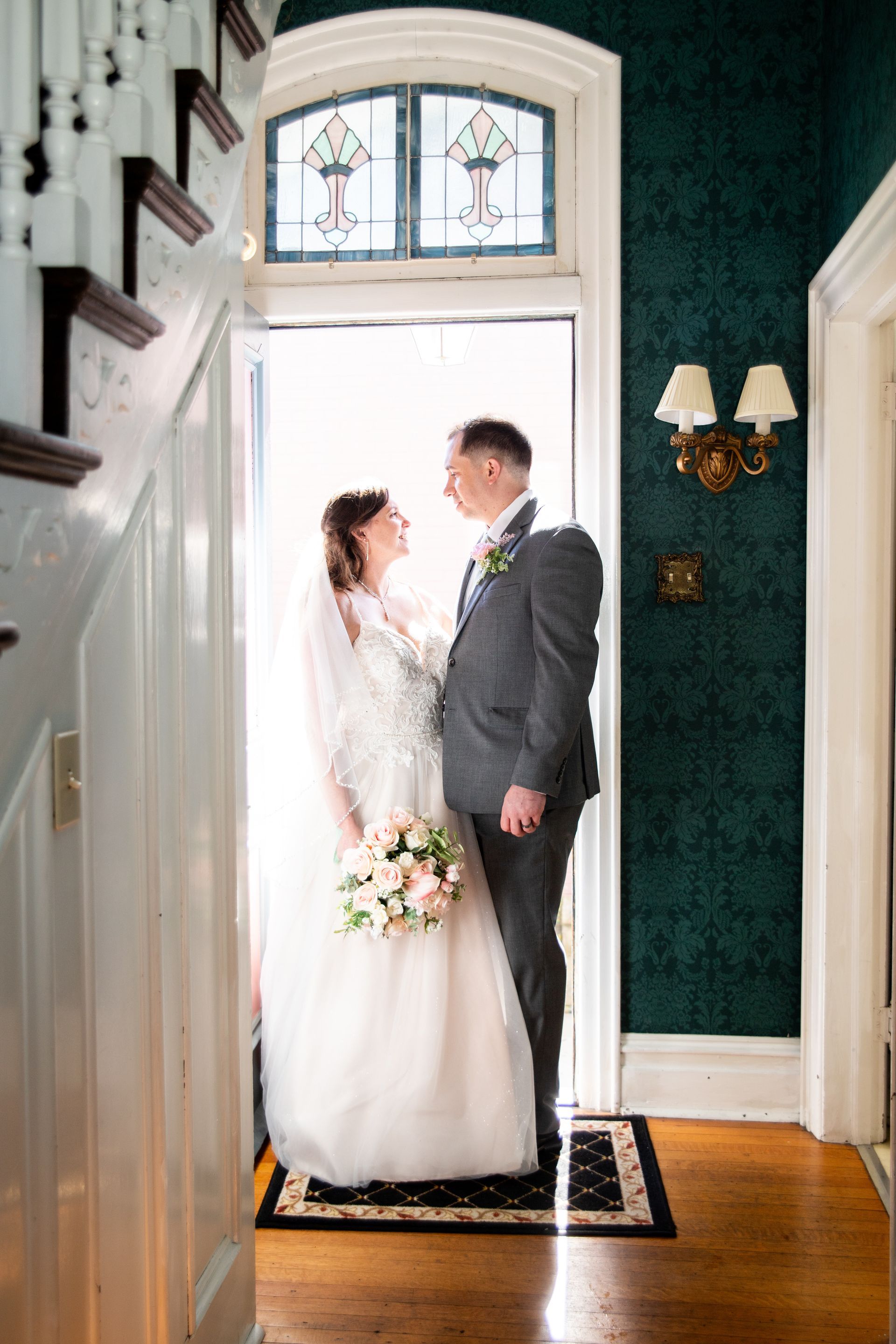 A bride and groom are standing in front of a door in a hallway.