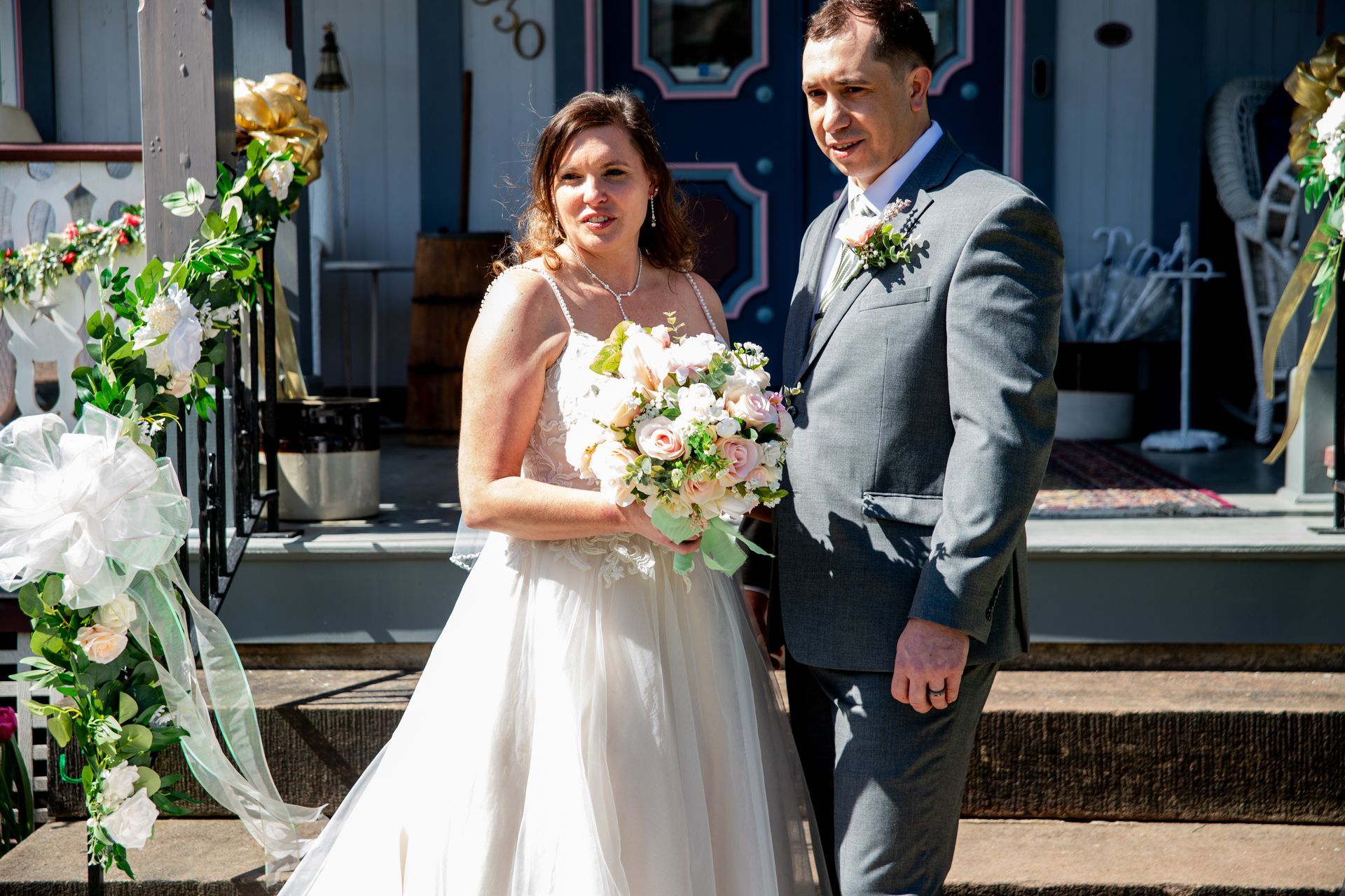 A bride and groom are posing for a picture in front of a house.