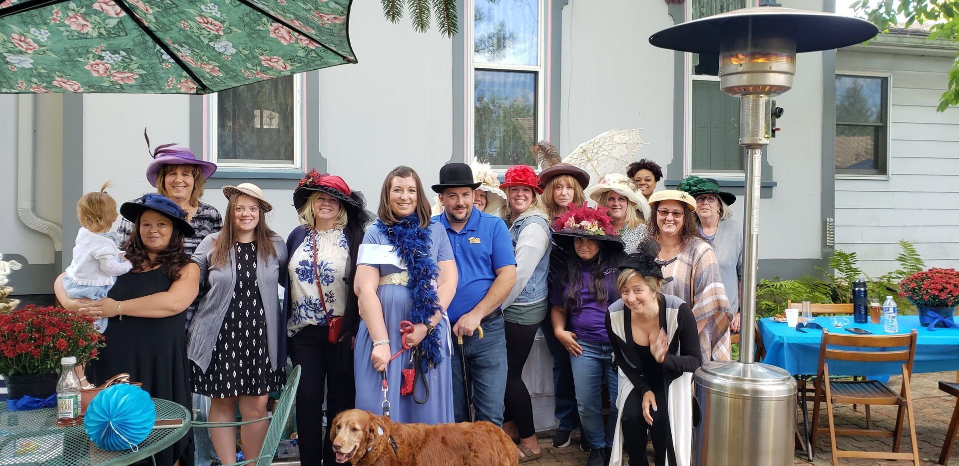 A group of people wearing hats are posing for a picture in front of a house.